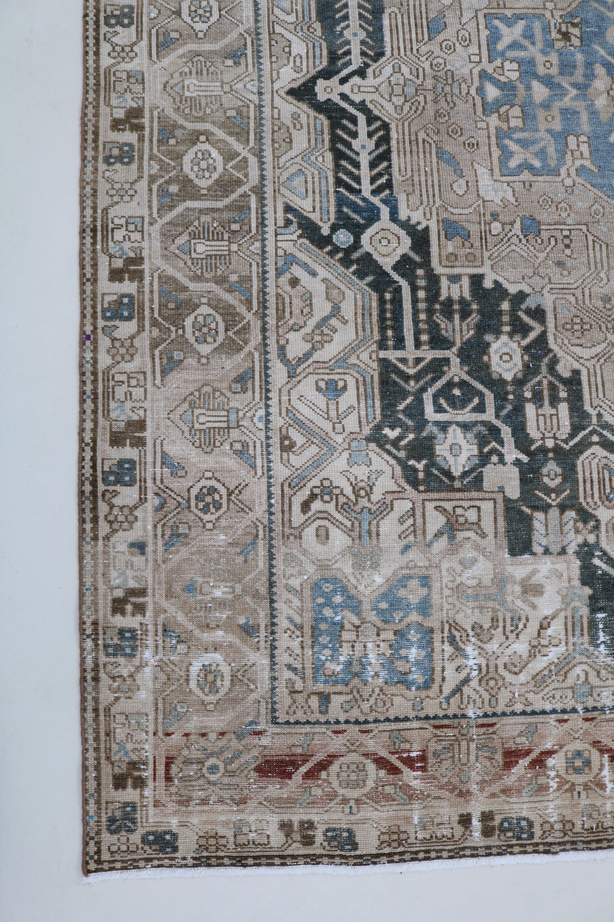 Antique Persian Karaja carpet with pale beige field, blue geometric motifs and dark detailed border
