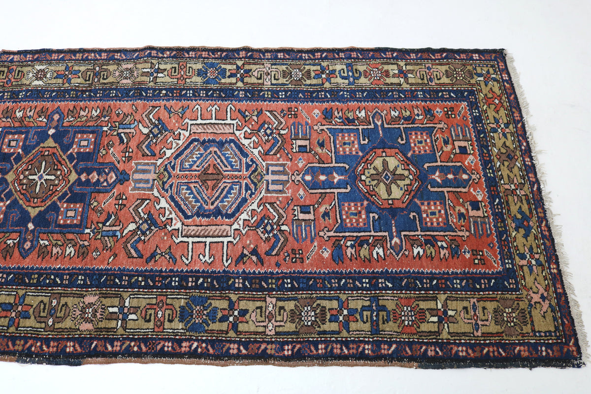 Angled view of Persian Karaja runner featuring rust red, deep blue and camel tones