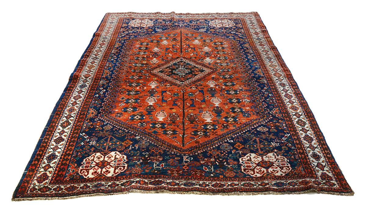 Full view of antique Qashqai carpet with central medallion in rust red and indigo