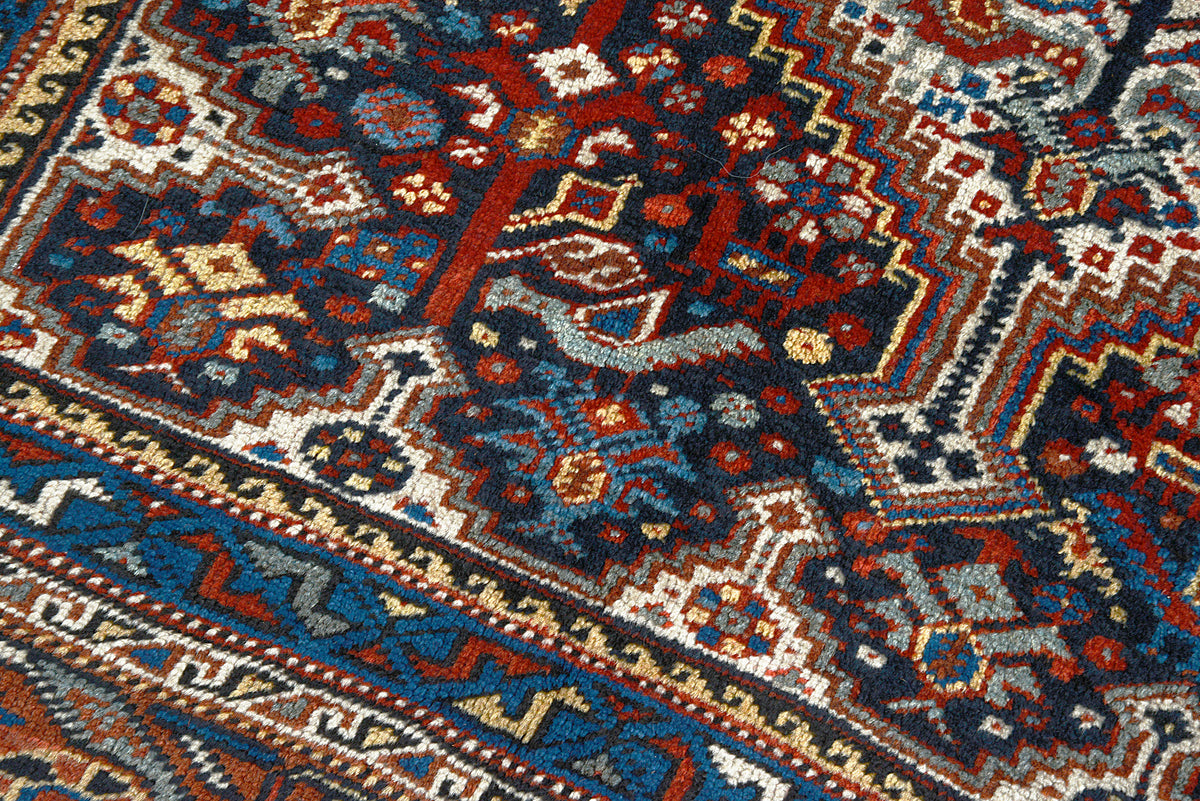 Close-up of antique Persian Qashqai carpet showing dense geometric patterning and aged wool texture
