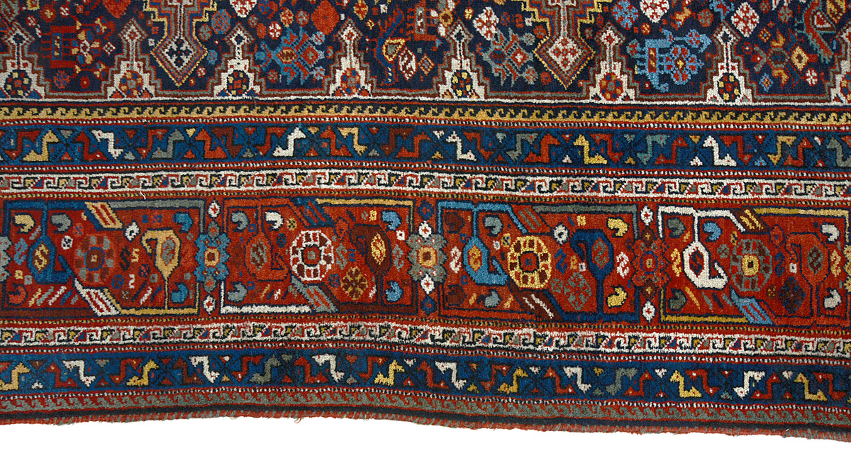 Close-up of antique Qashqai carpet border featuring layered tribal patterns in red and blue