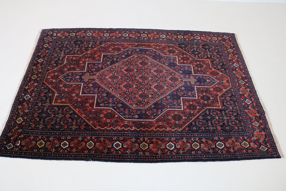 Angled view of Persian Senneh rug with layered geometric medallion design