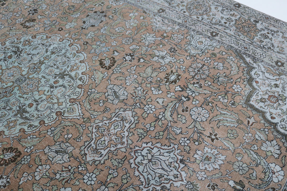 Angled detail of antique Tabriz carpet with floral pattern and ornate border