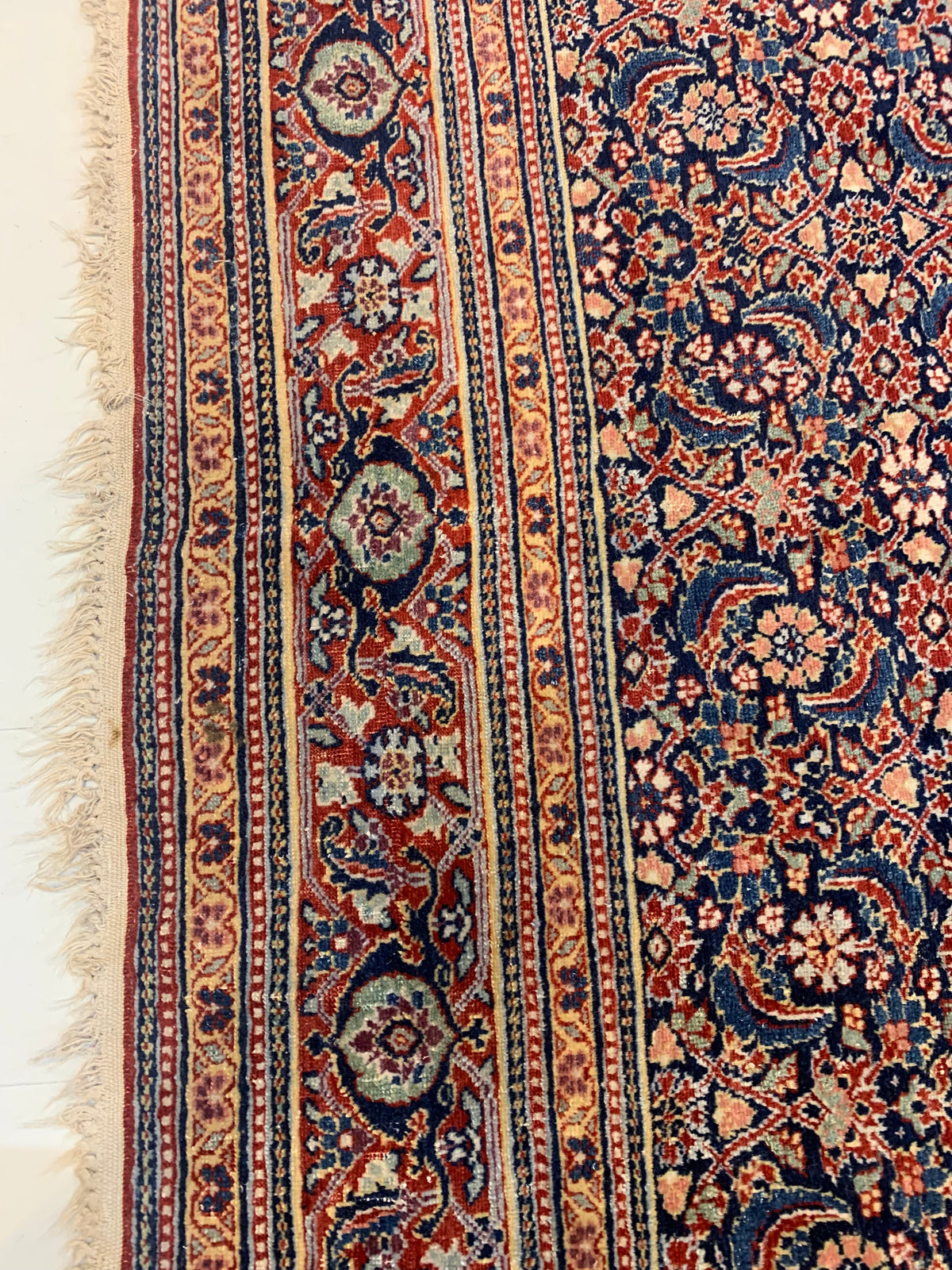 Detailed rug edge featuring floral motifs and multiple contrasting borders