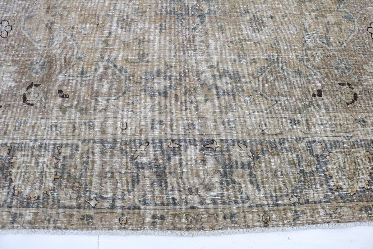 Detailed border of Persian Tabriz carpet with faded geometric and floral patterns