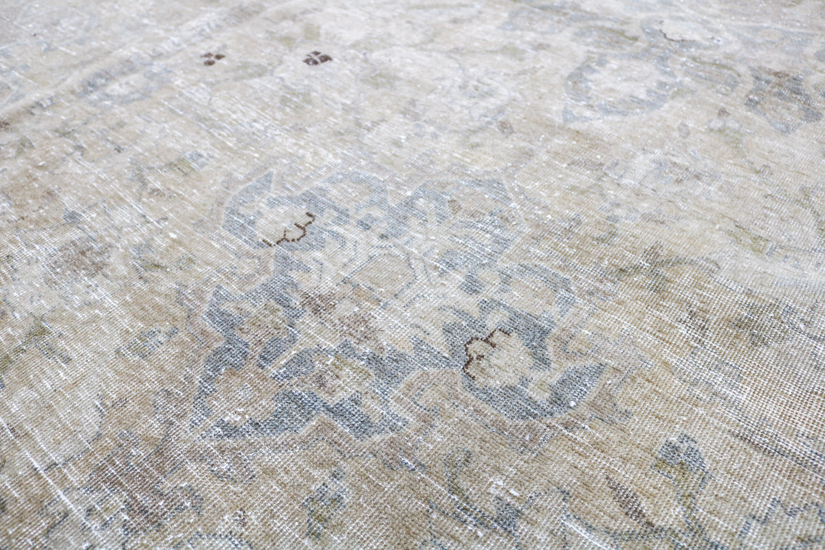 Detailed antique carpet surface with delicate floral patterns and muted blue accents