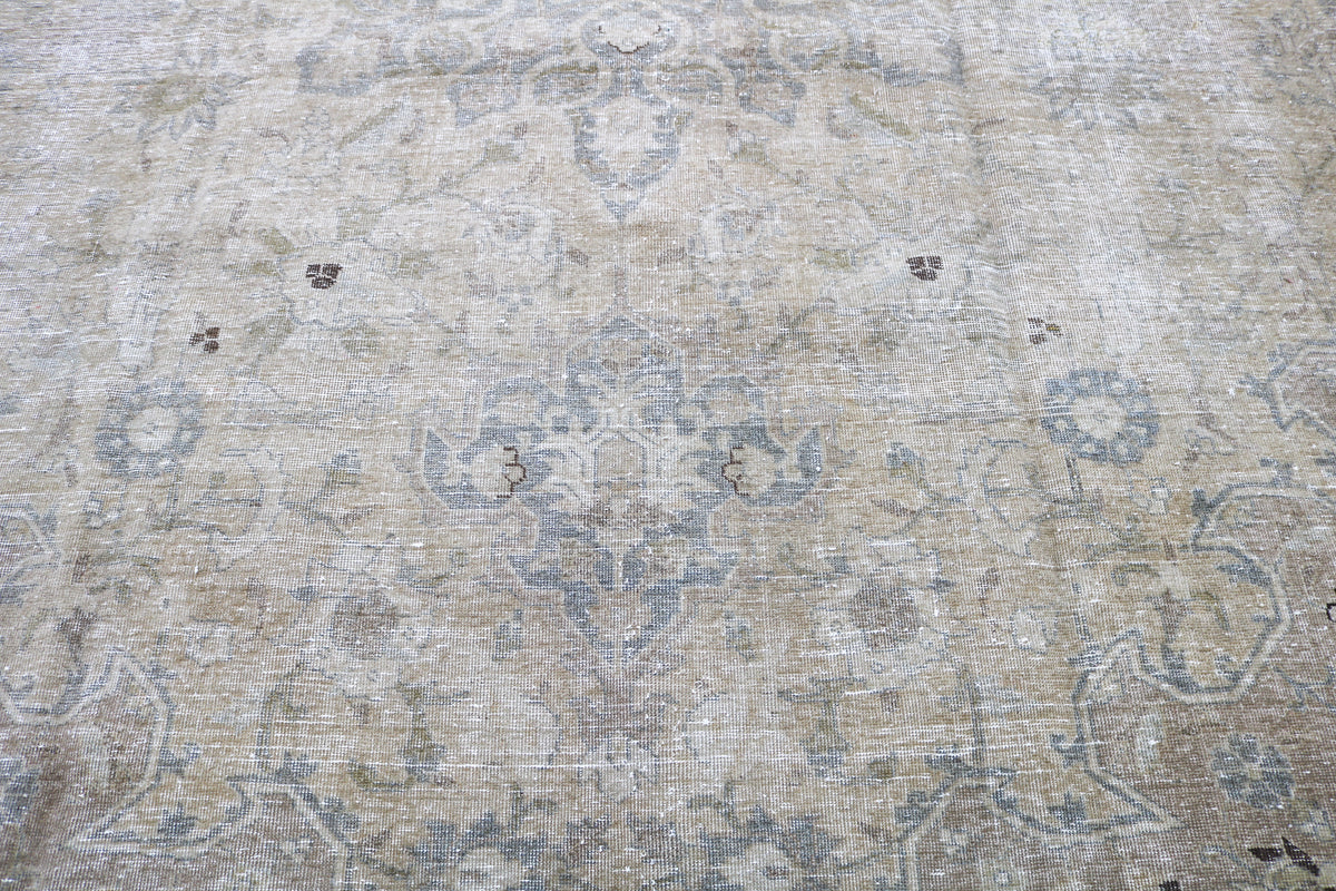 Close-up of antique Tabriz carpet showing delicate floral patterns in muted tones