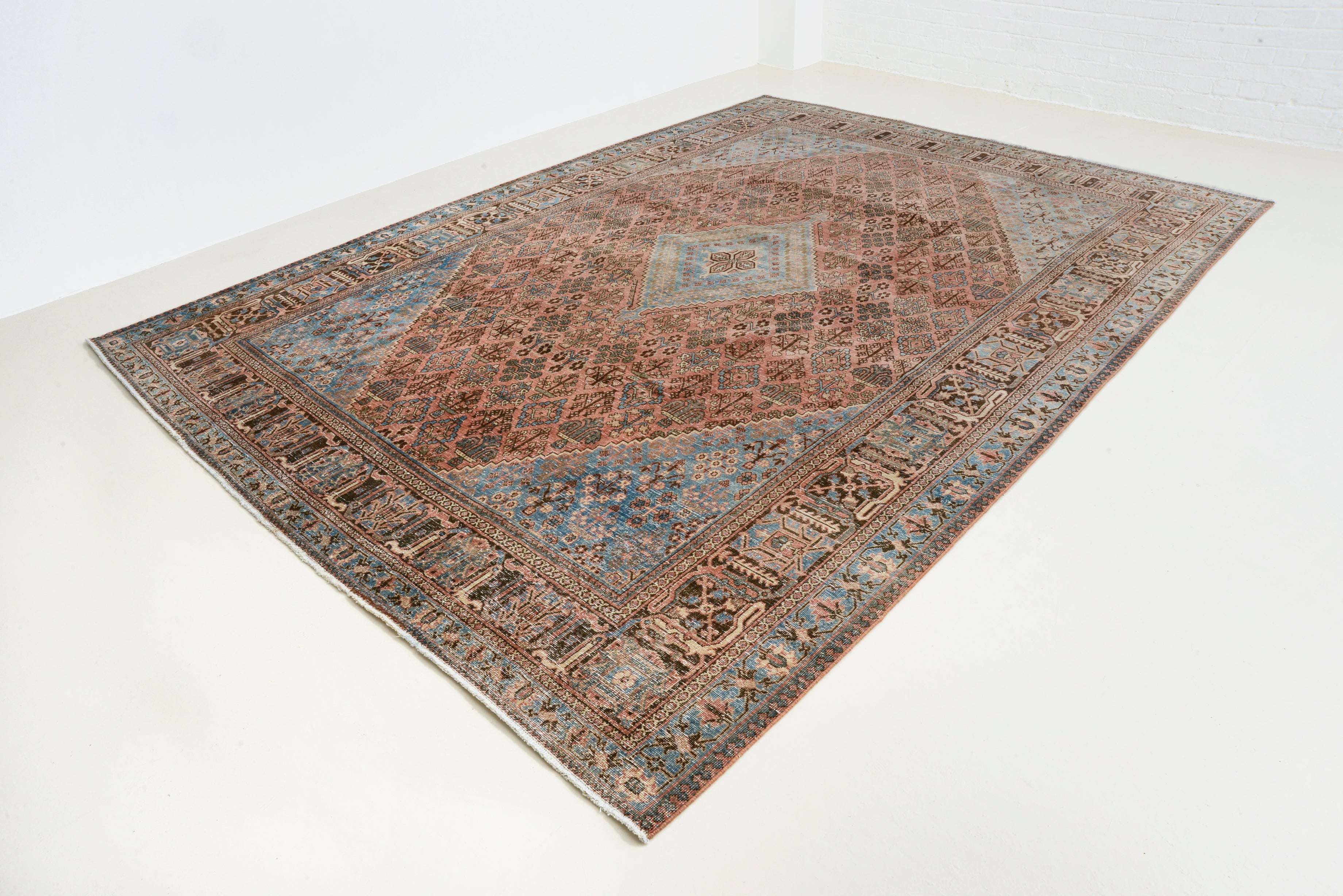 Angled view of antique Persian Josheqan rug showing overall pattern
