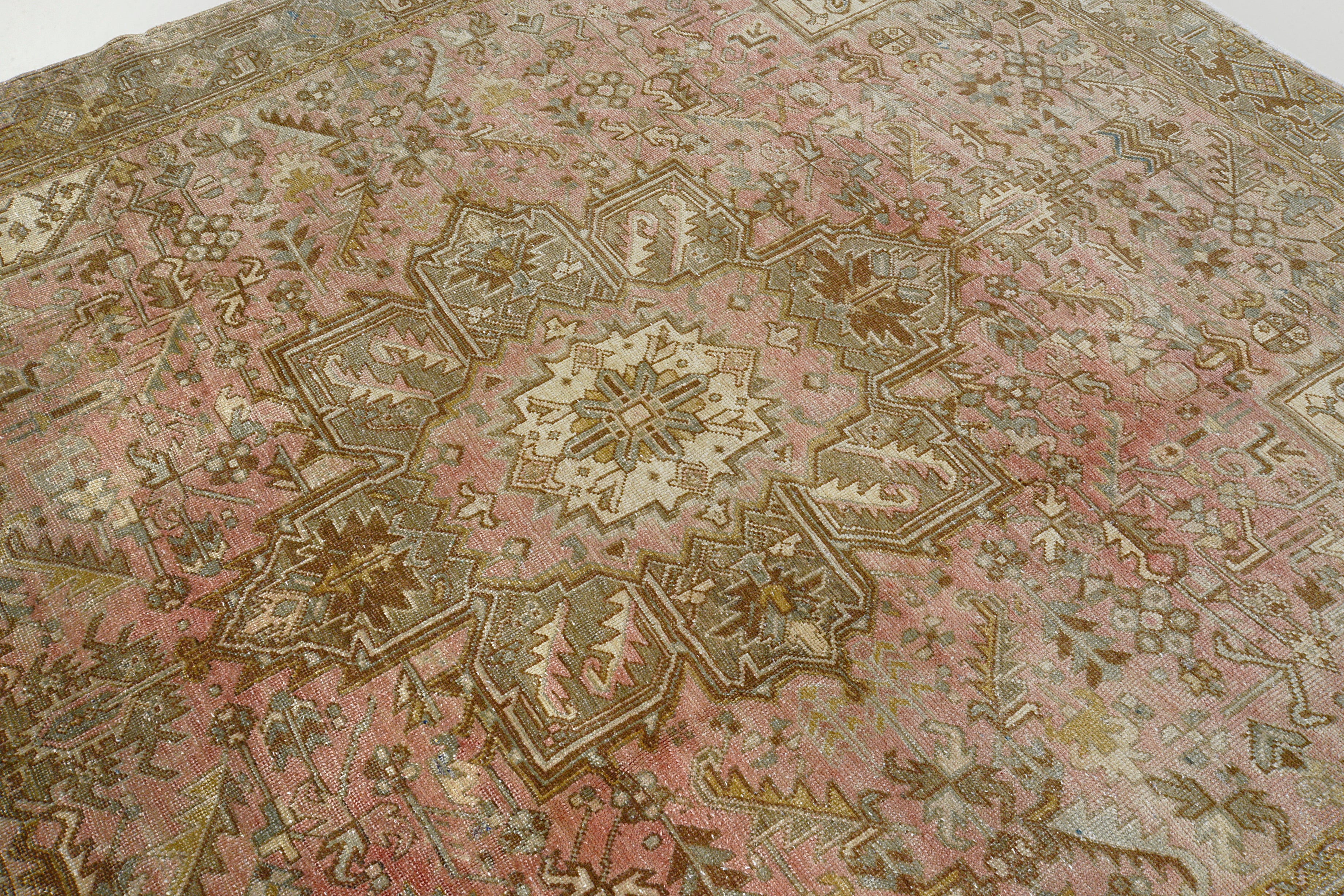 Detail of vintage Persian Heriz carpet showing wool texture, geometric motifs and natural colour variation from age and use
