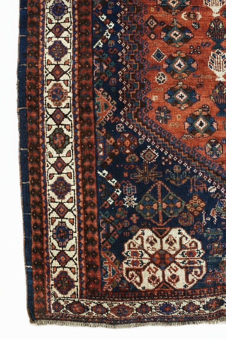 Corner view of an antique Persian Qashqai carpet showing tribal border and field details
