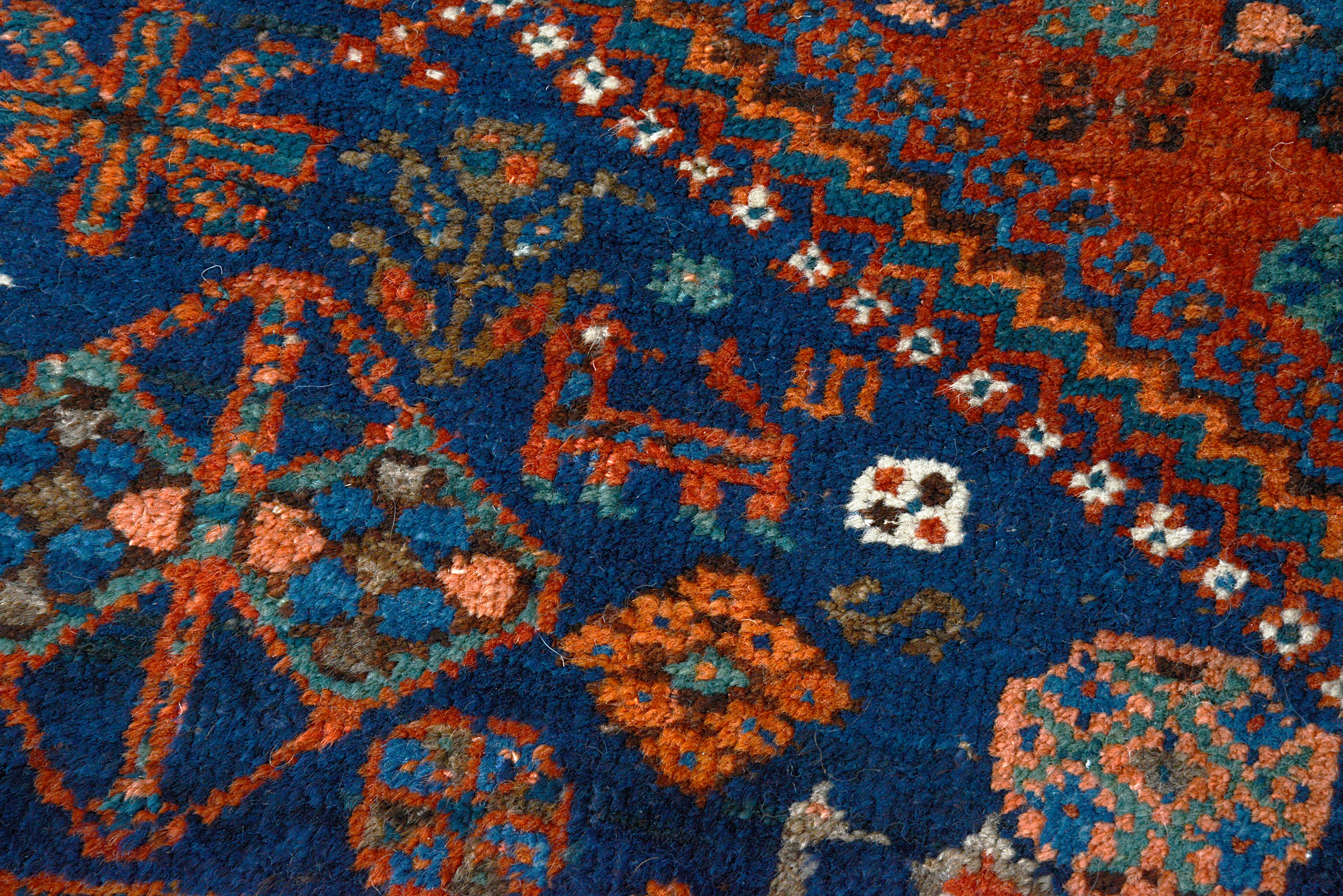 Close-up of richly colured tribal patterns on an antique Persian Qashqai carpet
