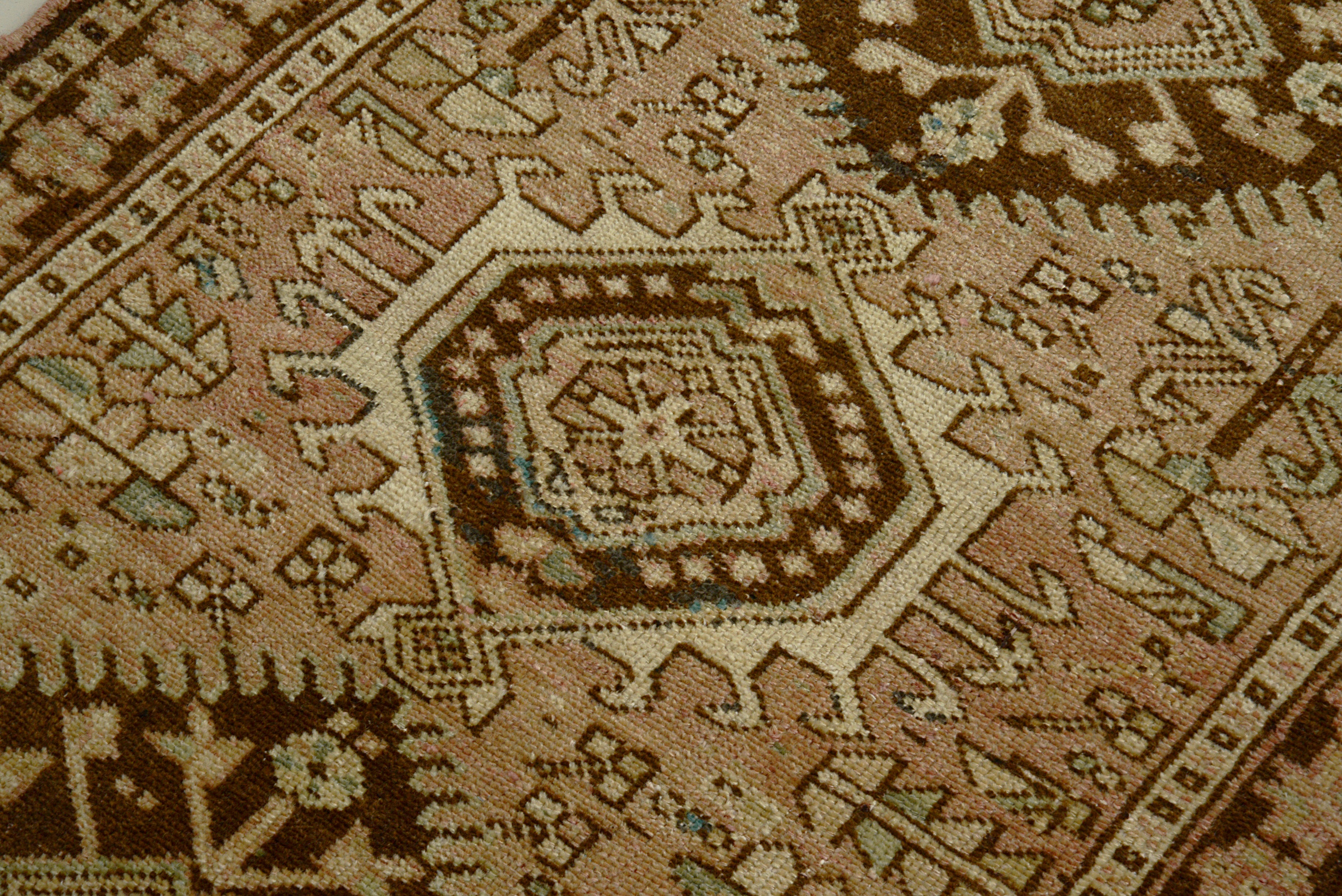 Close-up of a muted colour Antique Persian Heriz rug with geometric design