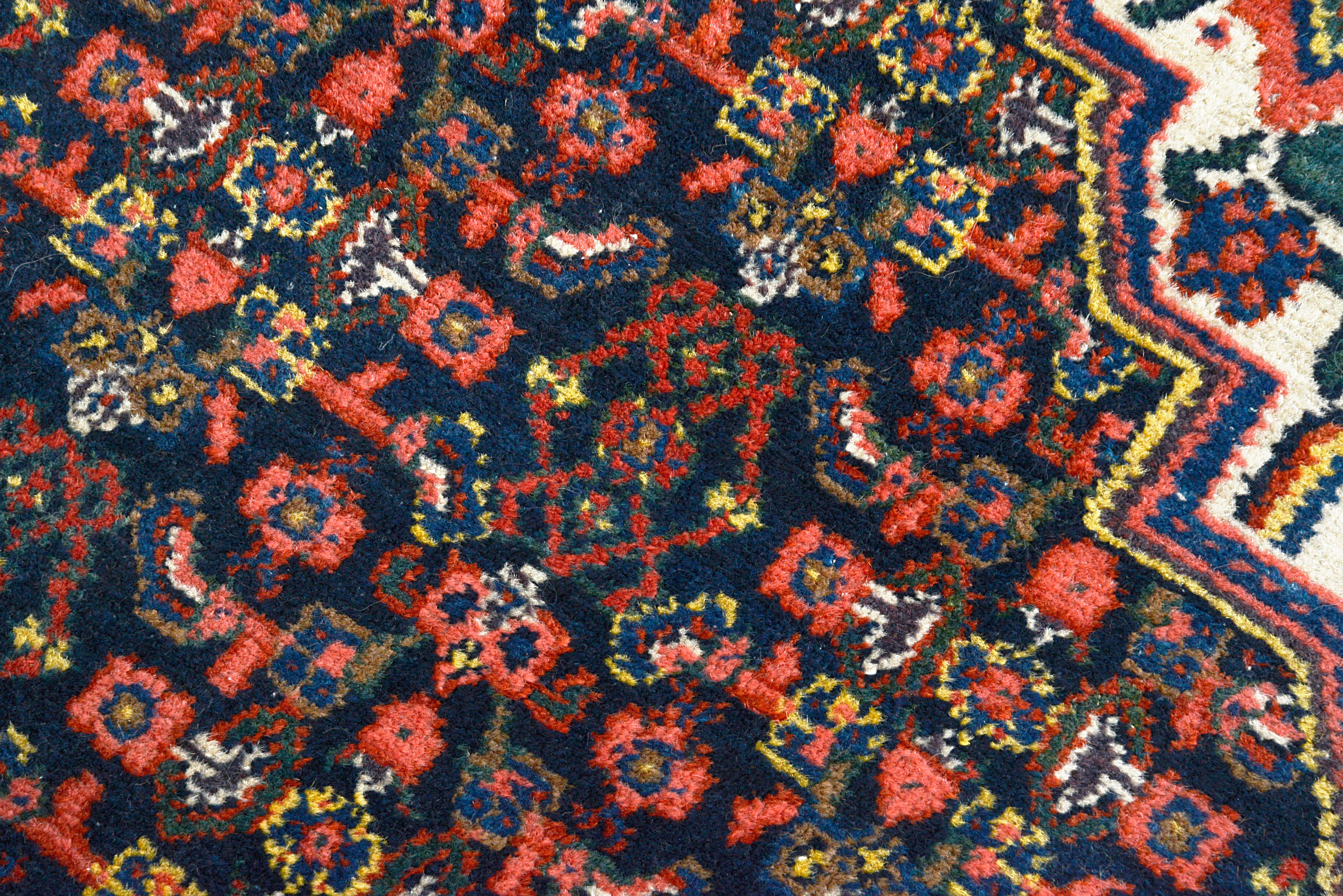 Close-up of a Antique Senneh rug with red, blue, and yellow colors.
