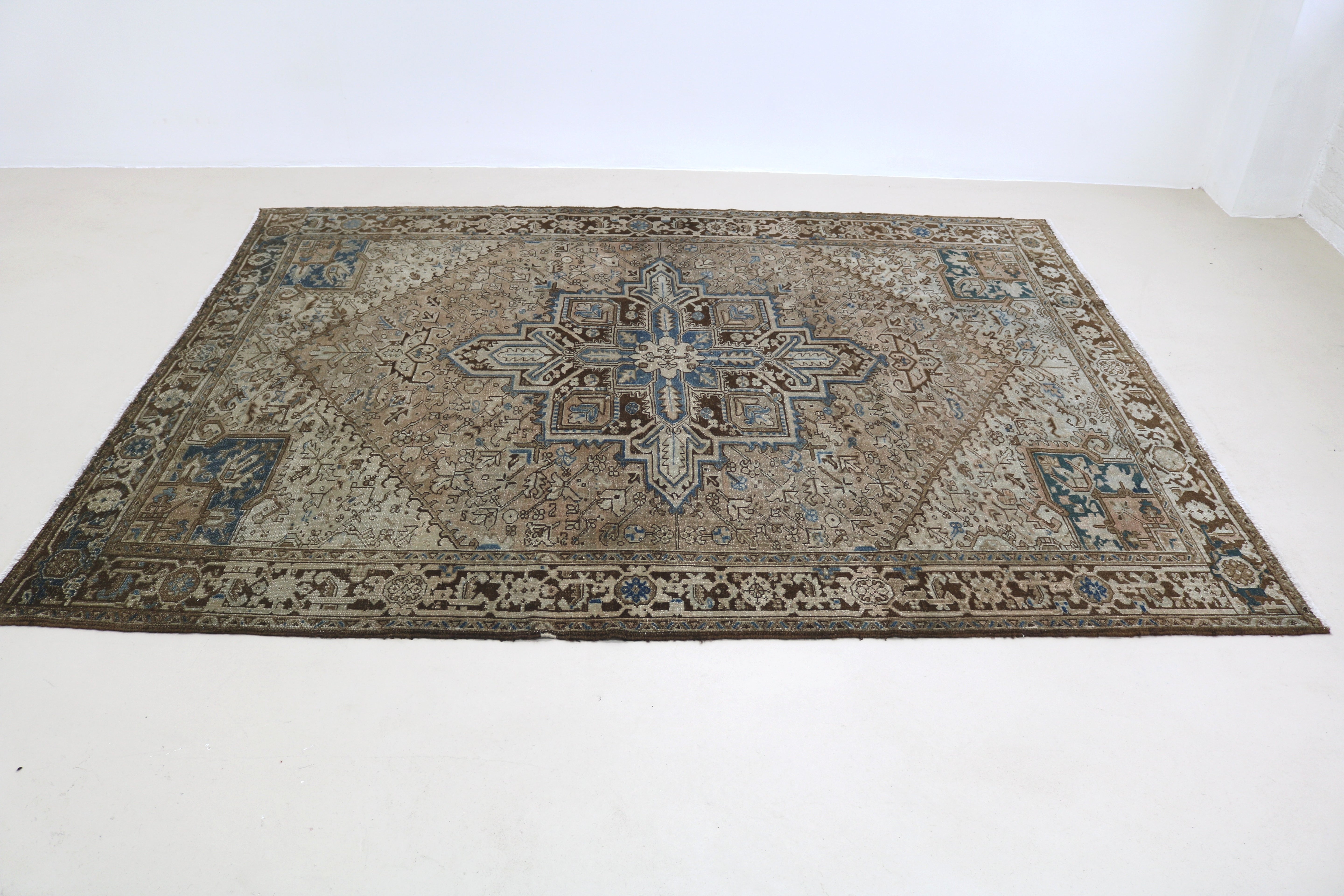 Perspective view of antique Persian Heriz carpet laid on floor
