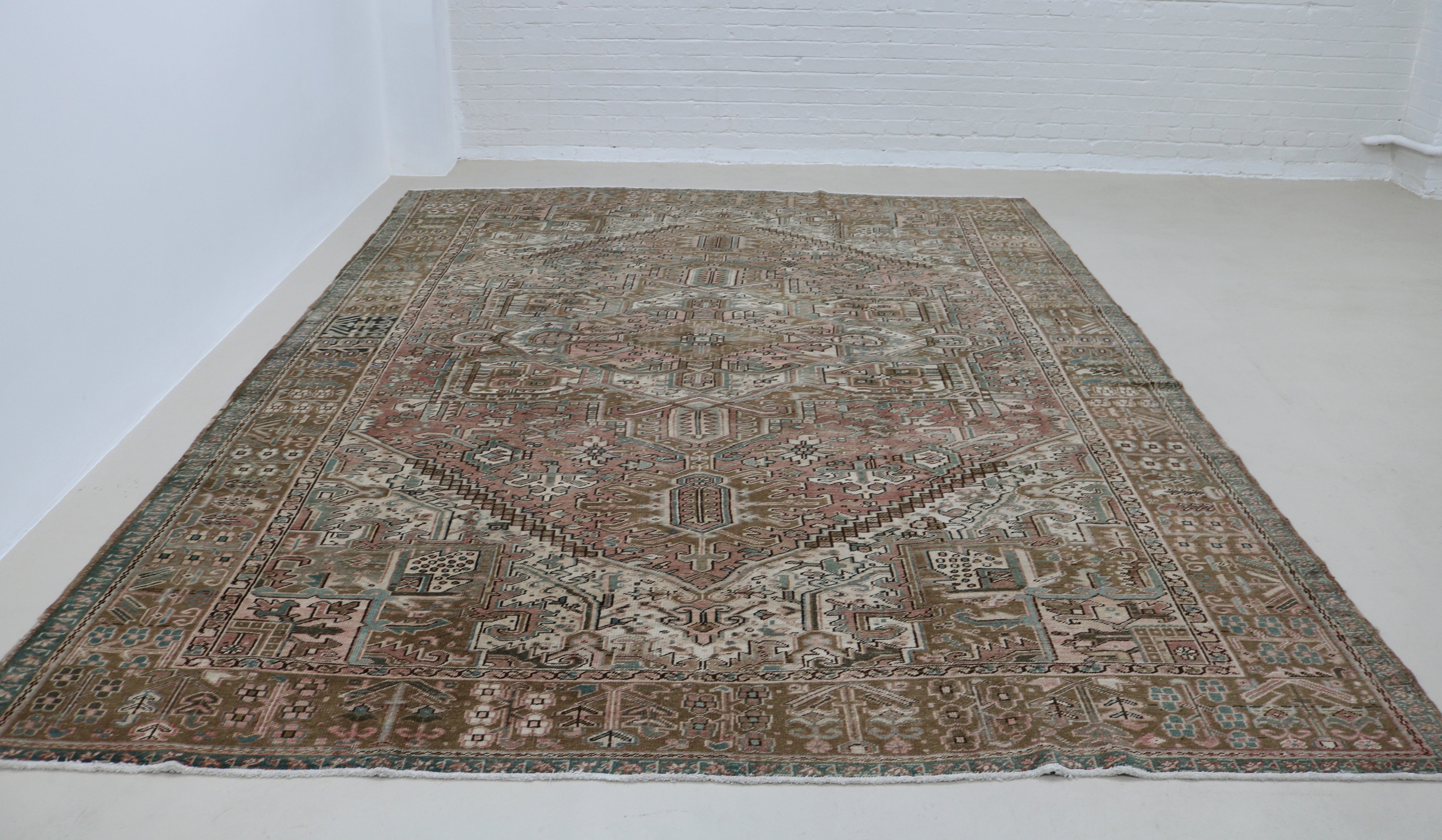 Perspective view of antique Persian Heriz carpet laid on floor
