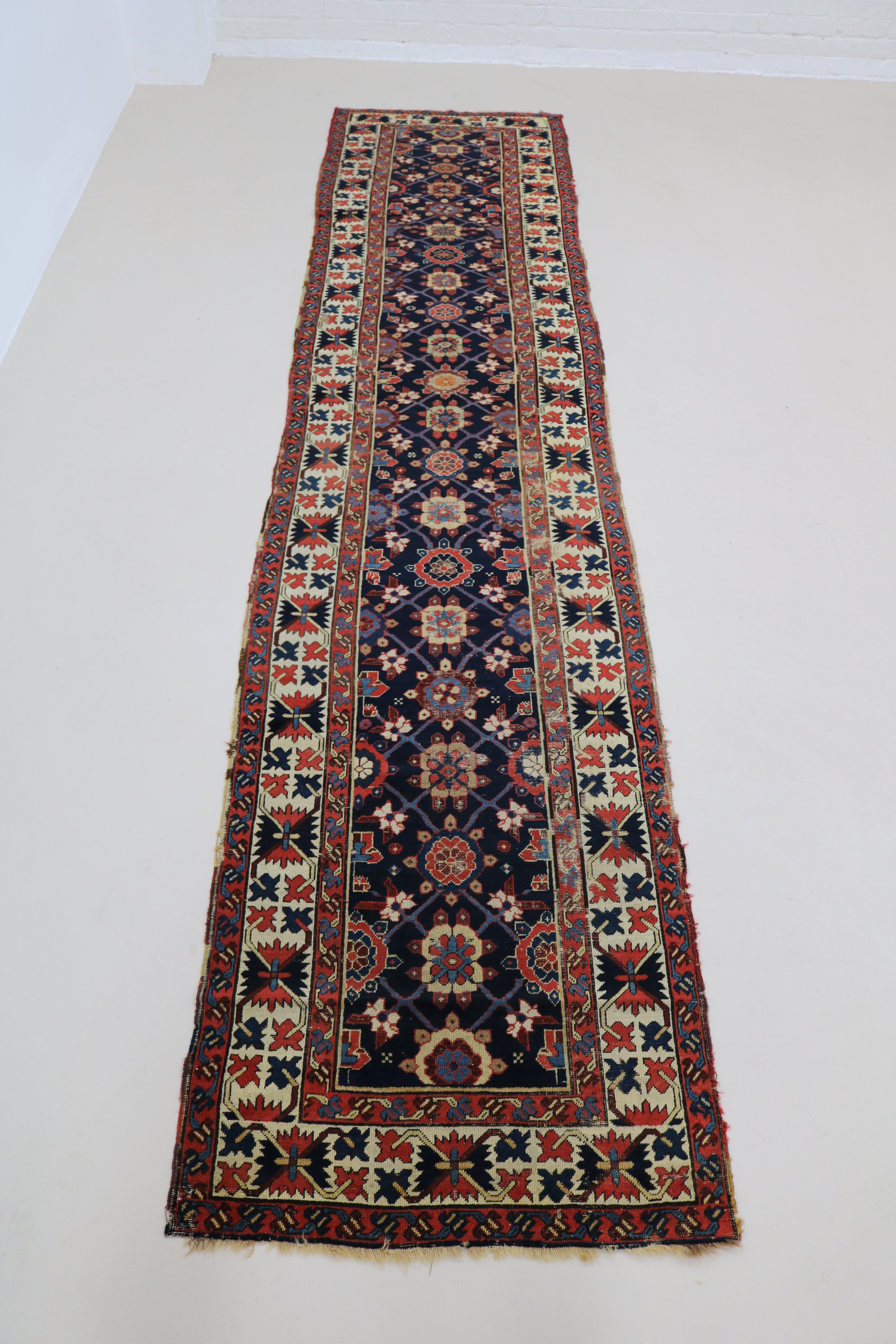 Full view of antique Caucasian Karabag runner with vibrant floral field and traditional borders
