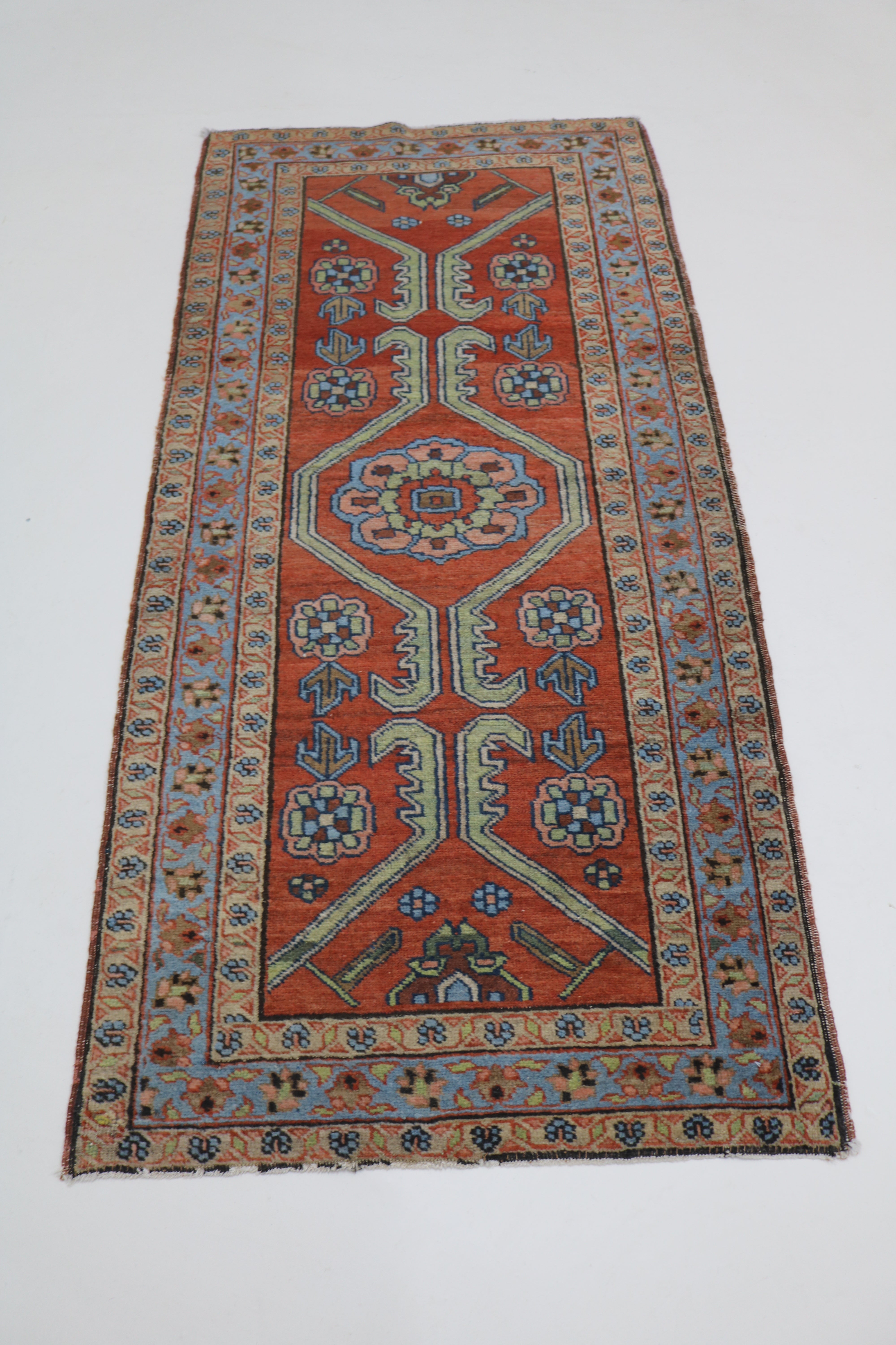 Full view of antique Persian Heriz rug with strong geometric field and traditional borders
