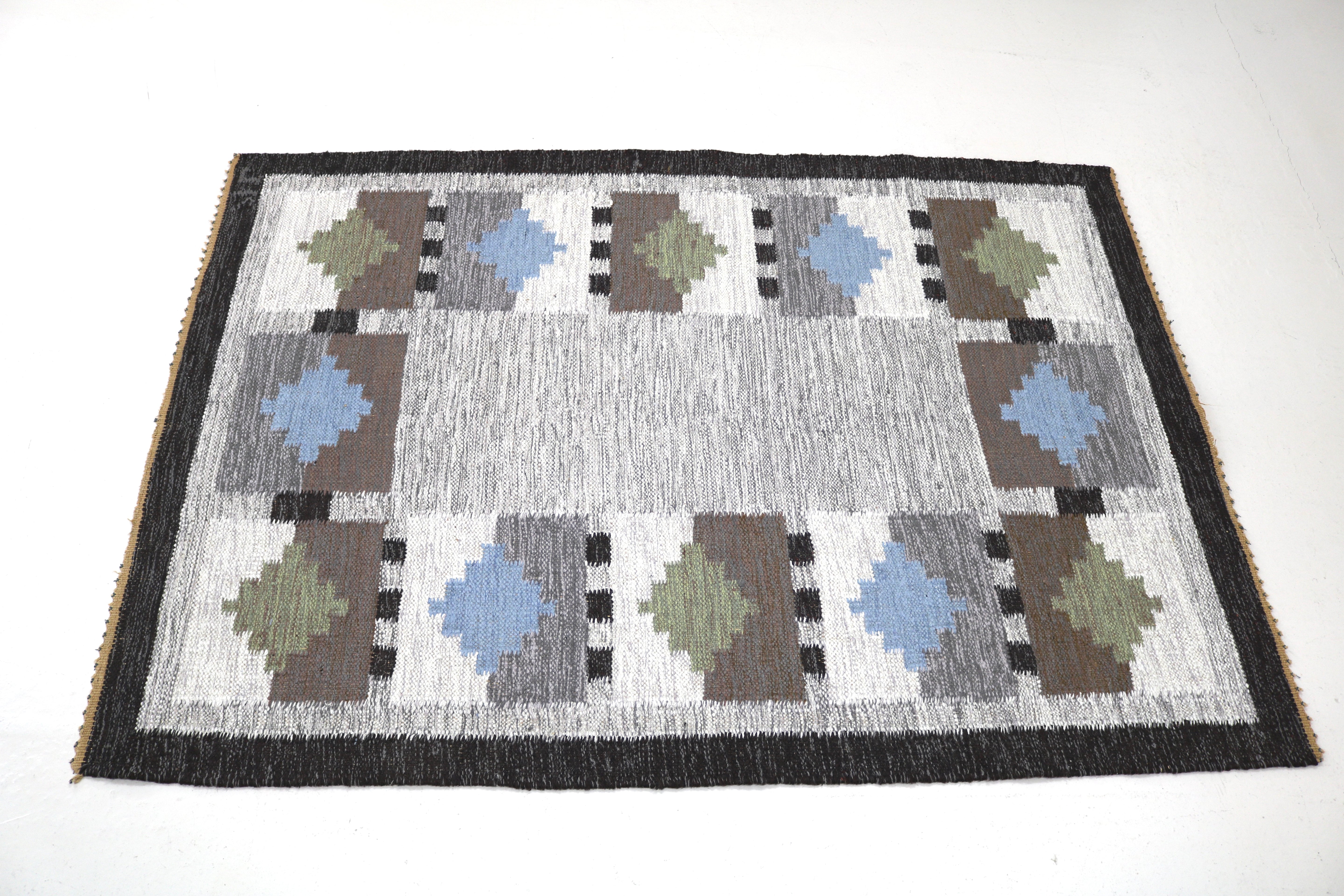 Close-up of handwoven Swedish kilim rug with blue and olive green geometric details