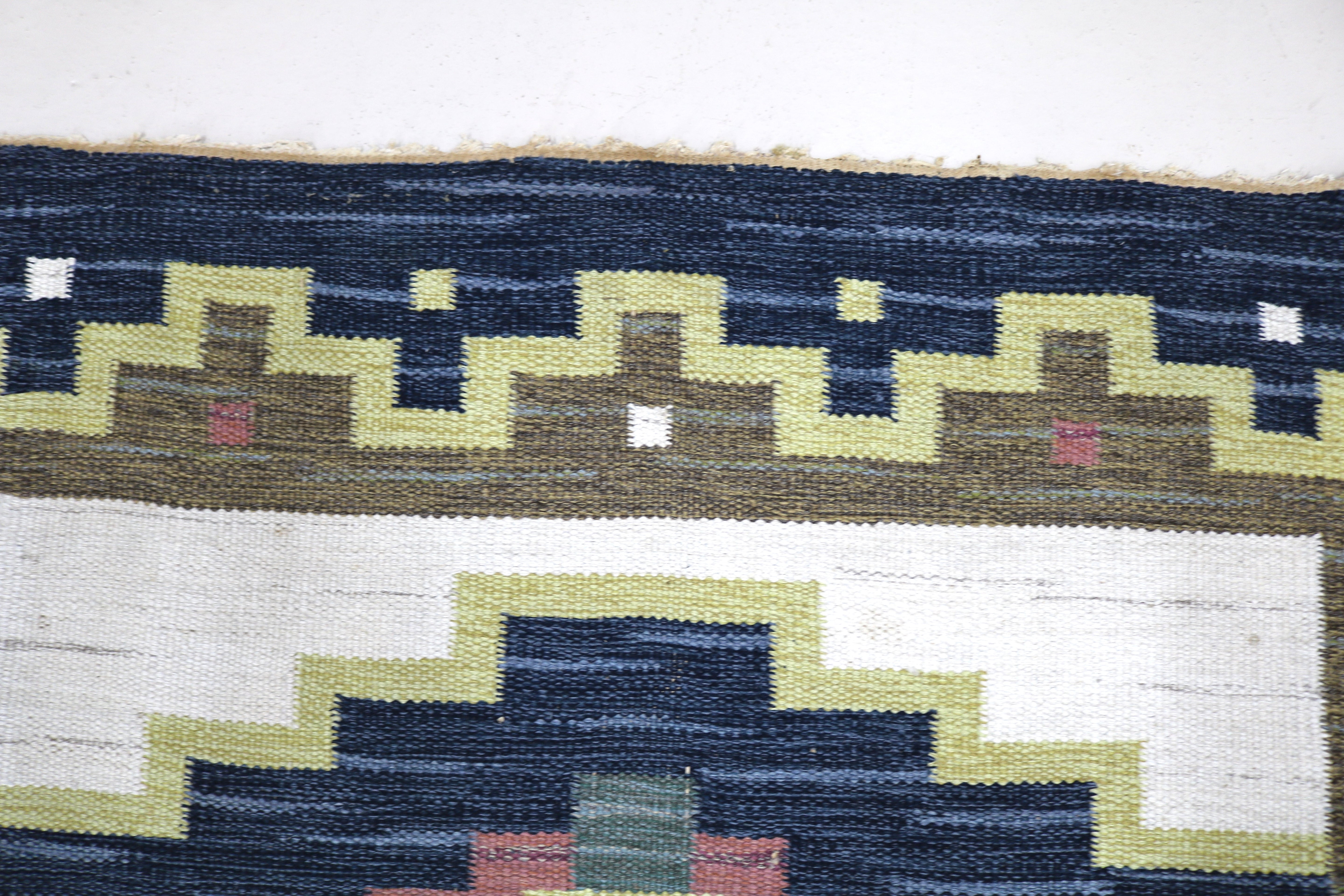 Corner detail of a vintage Swedish wool rug with geometric Scandinavian pattern.
