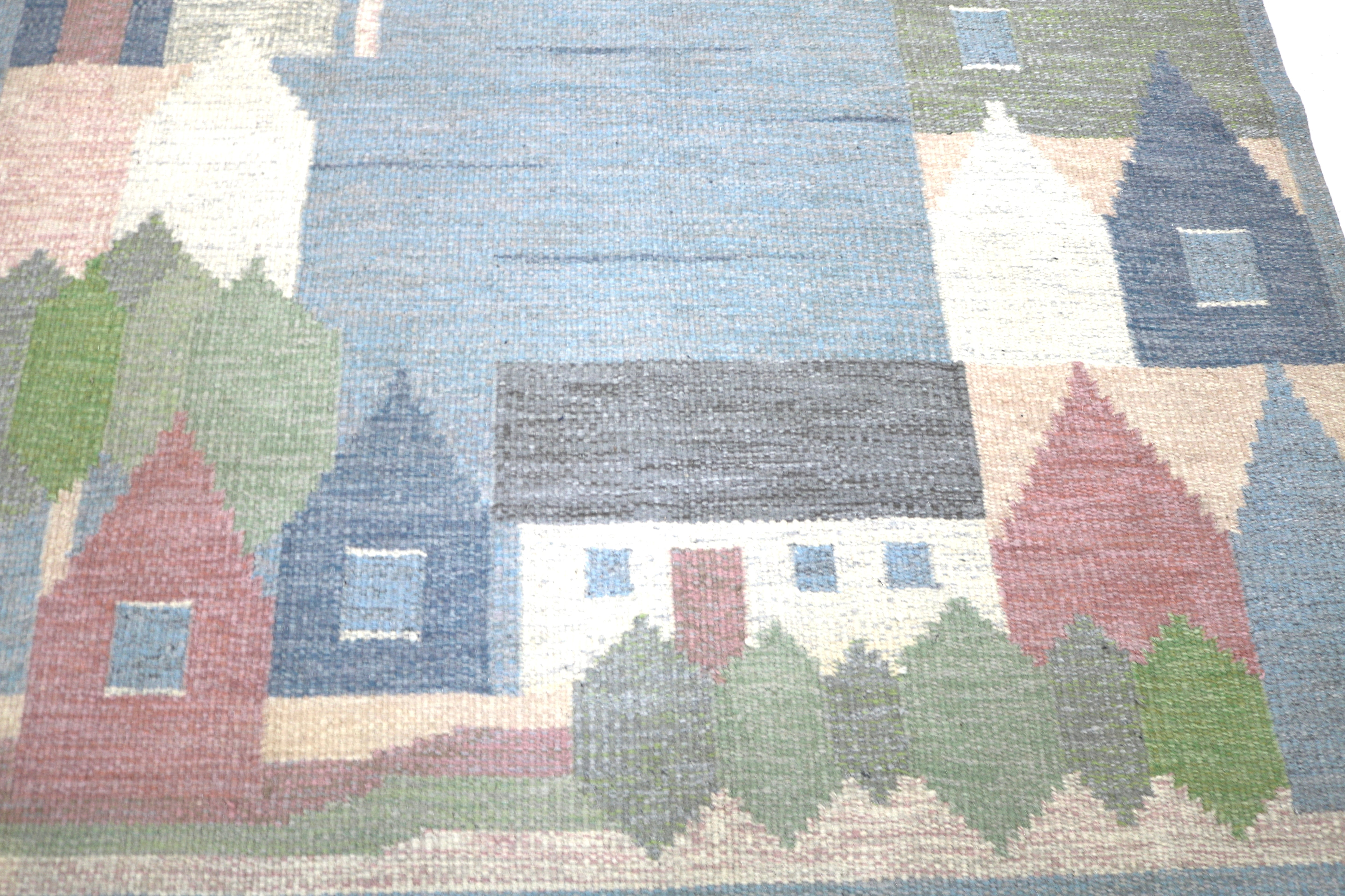 Close-up of handwoven Swedish village scene with pastel houses and trees.