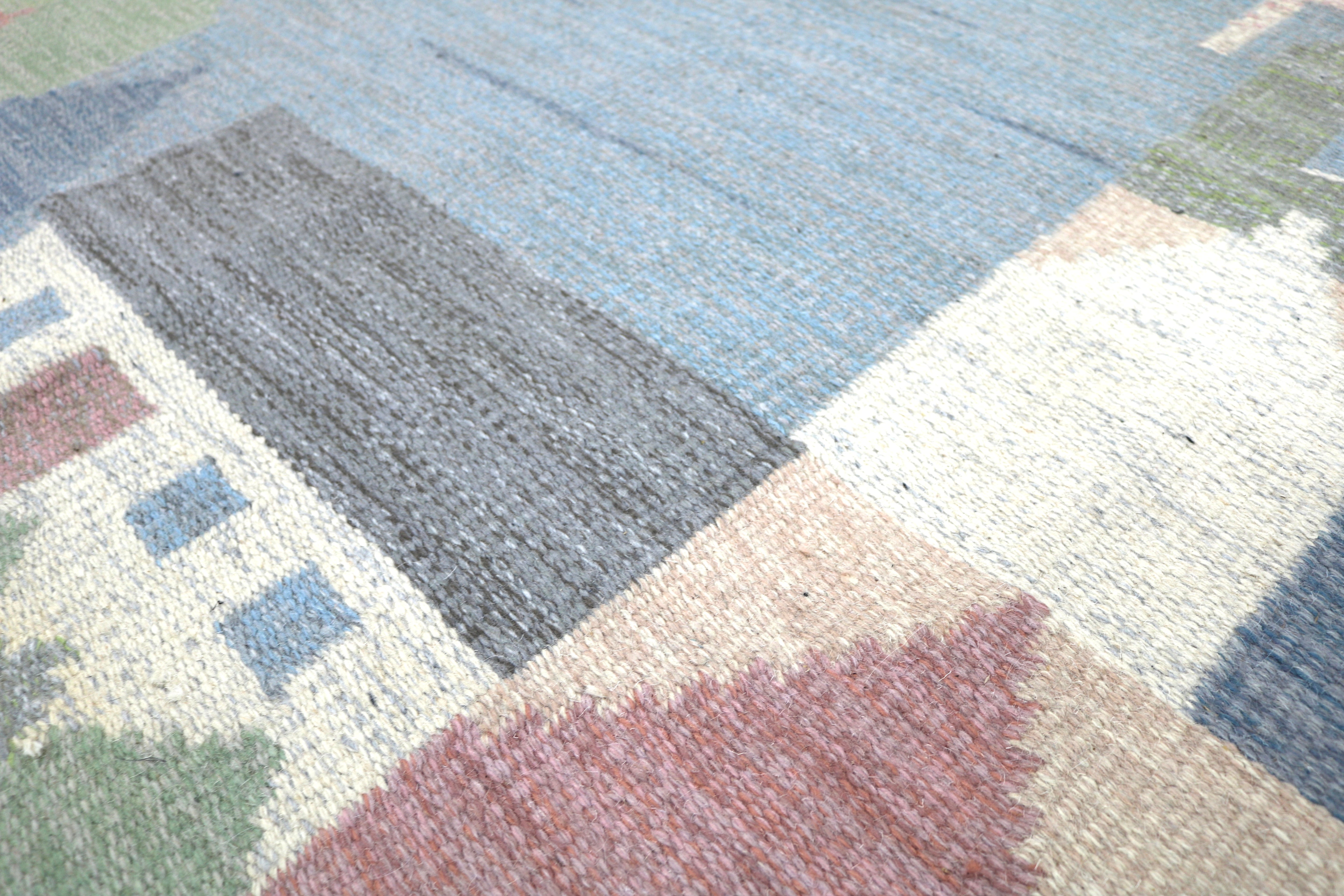 Corner detail of a vintage Swedish pictorial kilim with landscape motifs.