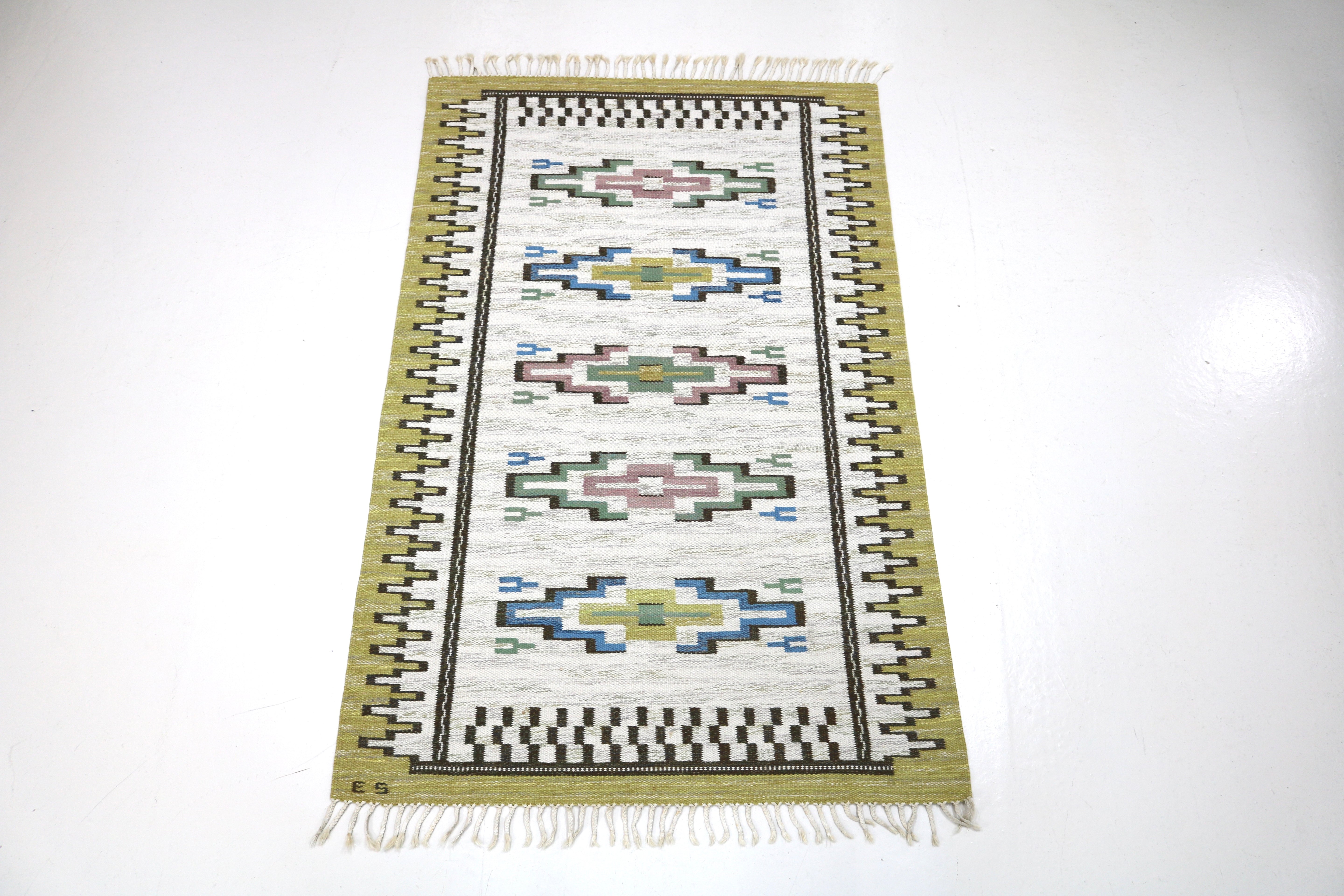 Handwoven Scandinavian kilim rug featuring repeating geometric woven motifs.