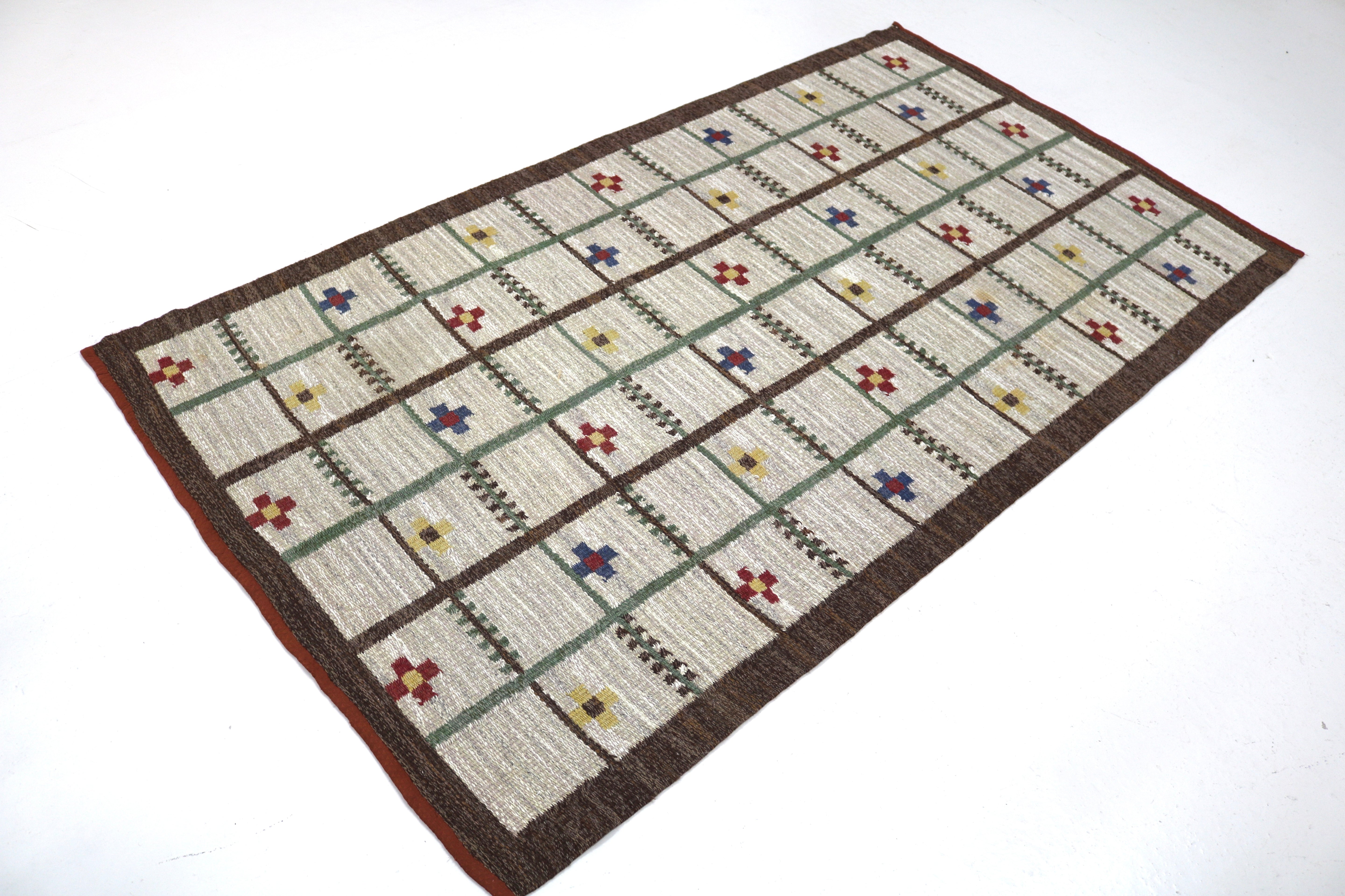 Angled view of a vintage Swedish flatweave rug with decorative lattice pattern.