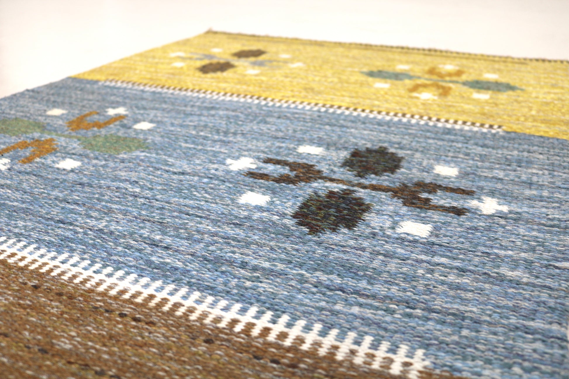 Detail of vintage Swedish kilim rug showing handwoven texture, geometric motifs, and natural wool colours
