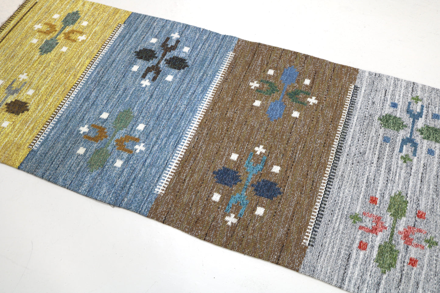 Detail of vintage Swedish kilim rug showing handwoven texture, geometric motifs, and natural wool colours
