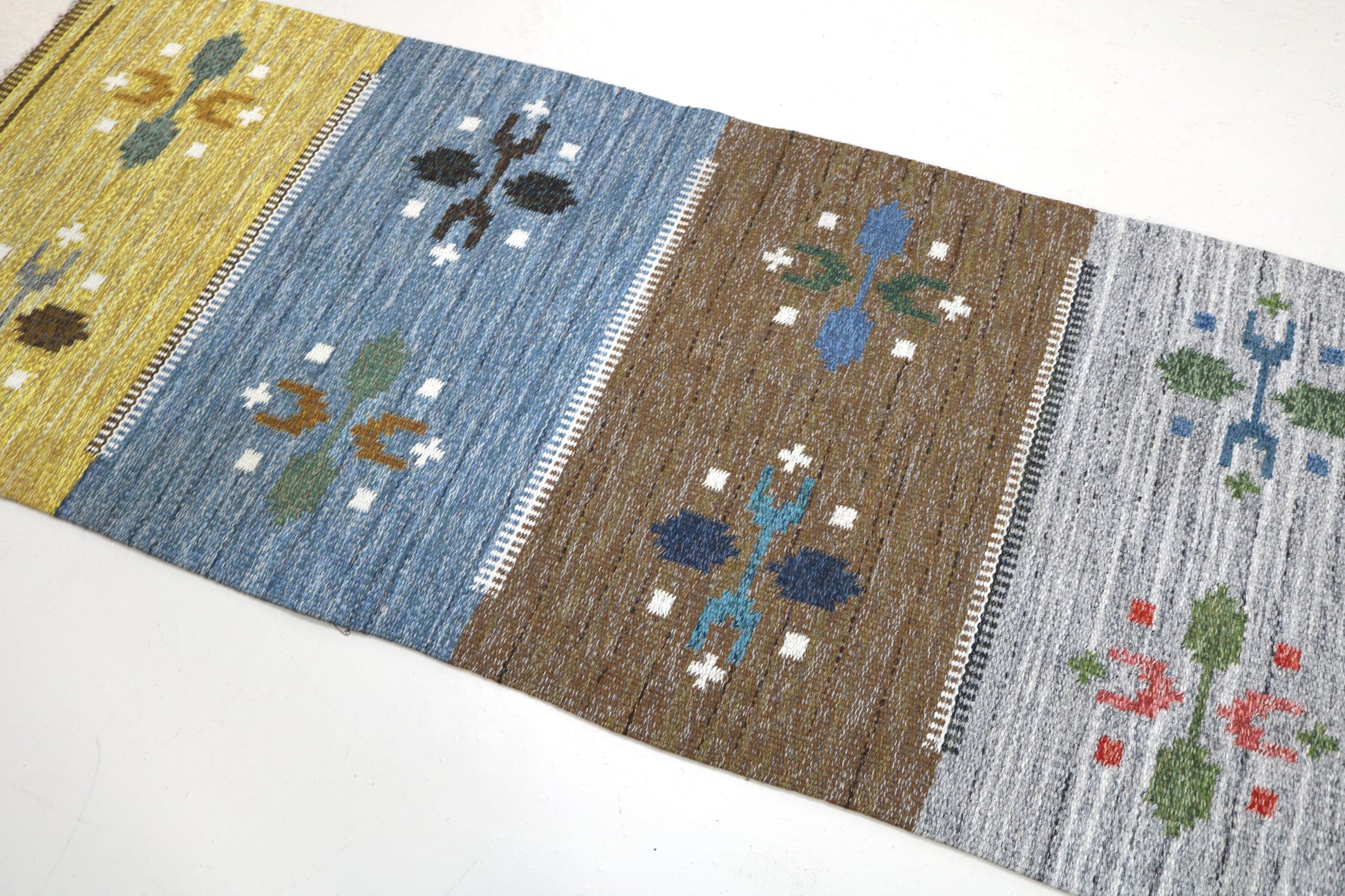 Detail of vintage Swedish kilim rug showing handwoven texture, geometric motifs, and natural wool colours
