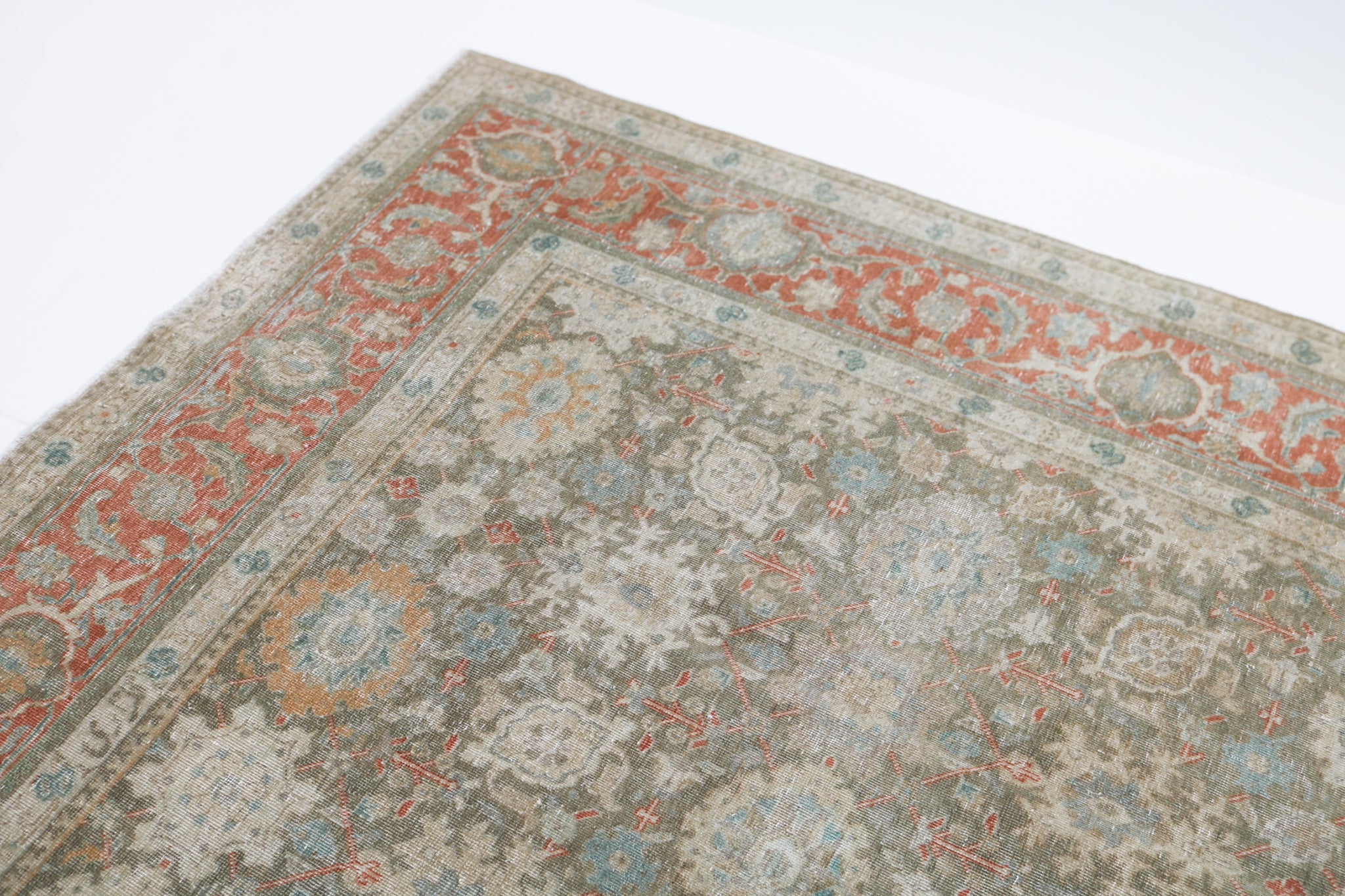 Close-up detail of antique Persian Heriz rug showing handwoven geometric motifs and natural wool colours