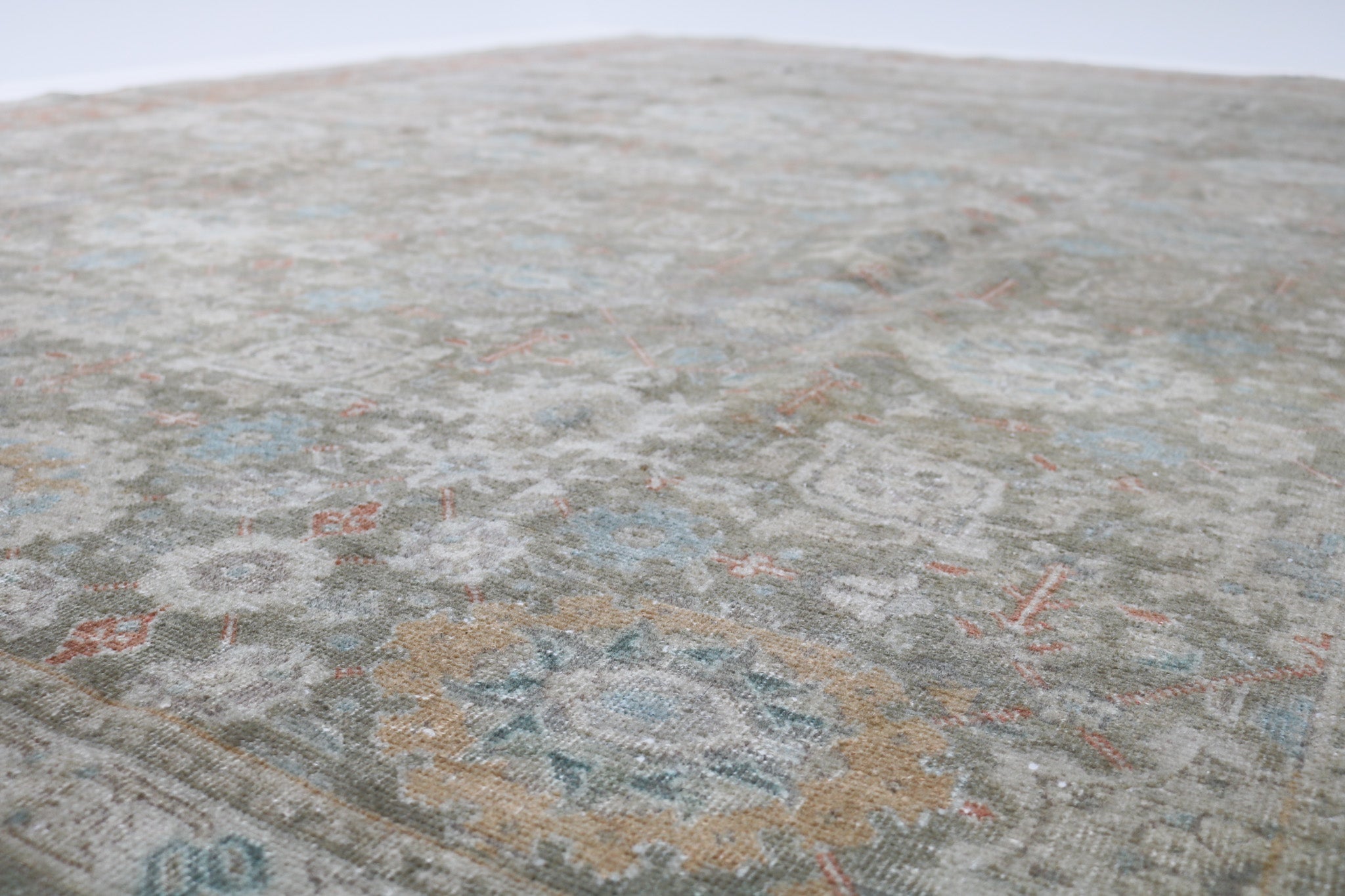 Close-up detail of antique Persian Heriz rug showing handwoven geometric motifs and natural wool colours
