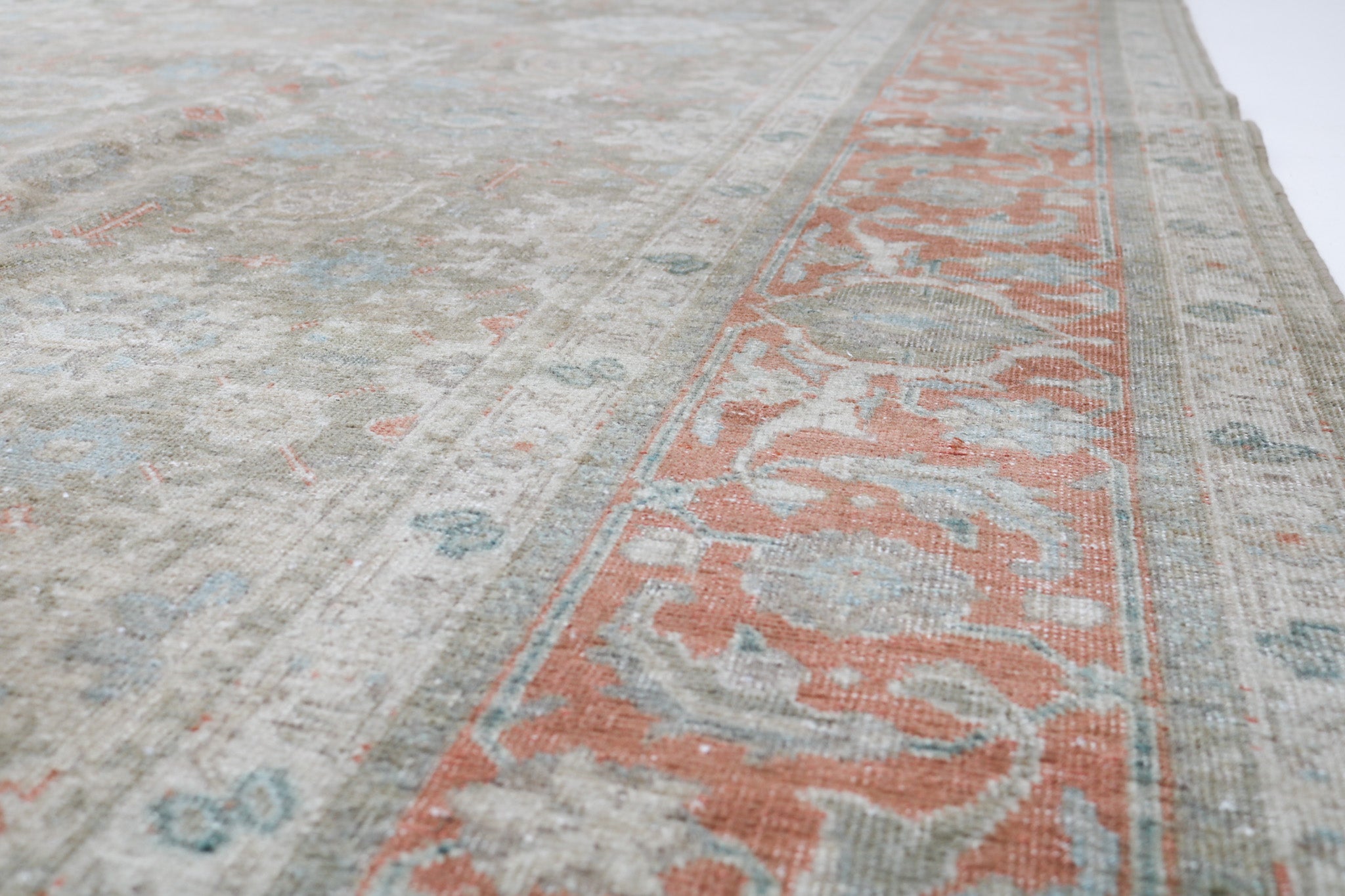 Close-up detail of antique Persian Heriz rug showing handwoven geometric motifs and natural wool colours