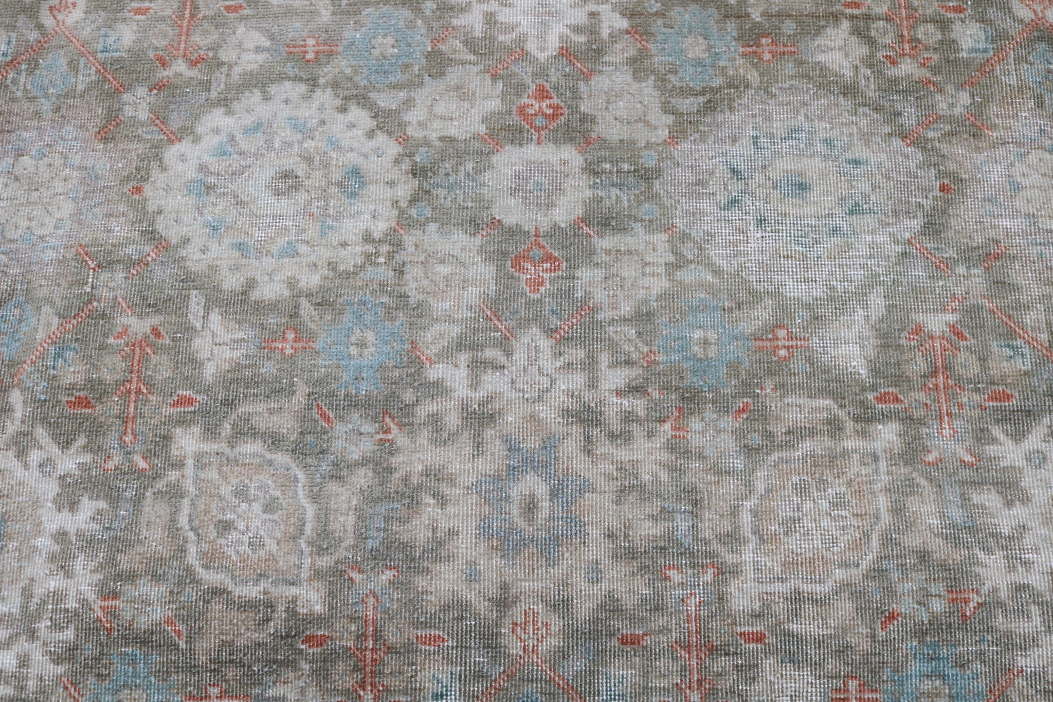 Close-up detail of antique Persian Heriz rug showing handwoven geometric motifs and natural wool colours