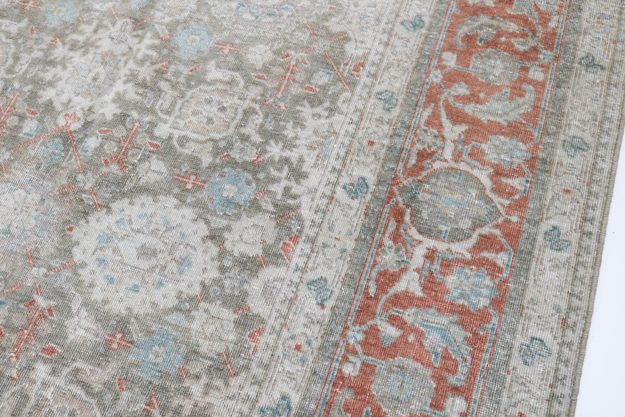 Close-up detail of antique Persian Heriz rug showing handwoven geometric motifs and natural wool colours