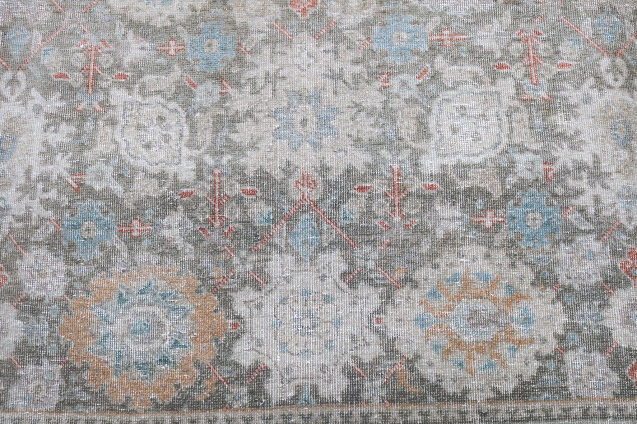 Close-up detail of antique Persian Heriz rug showing handwoven geometric motifs and natural wool colours