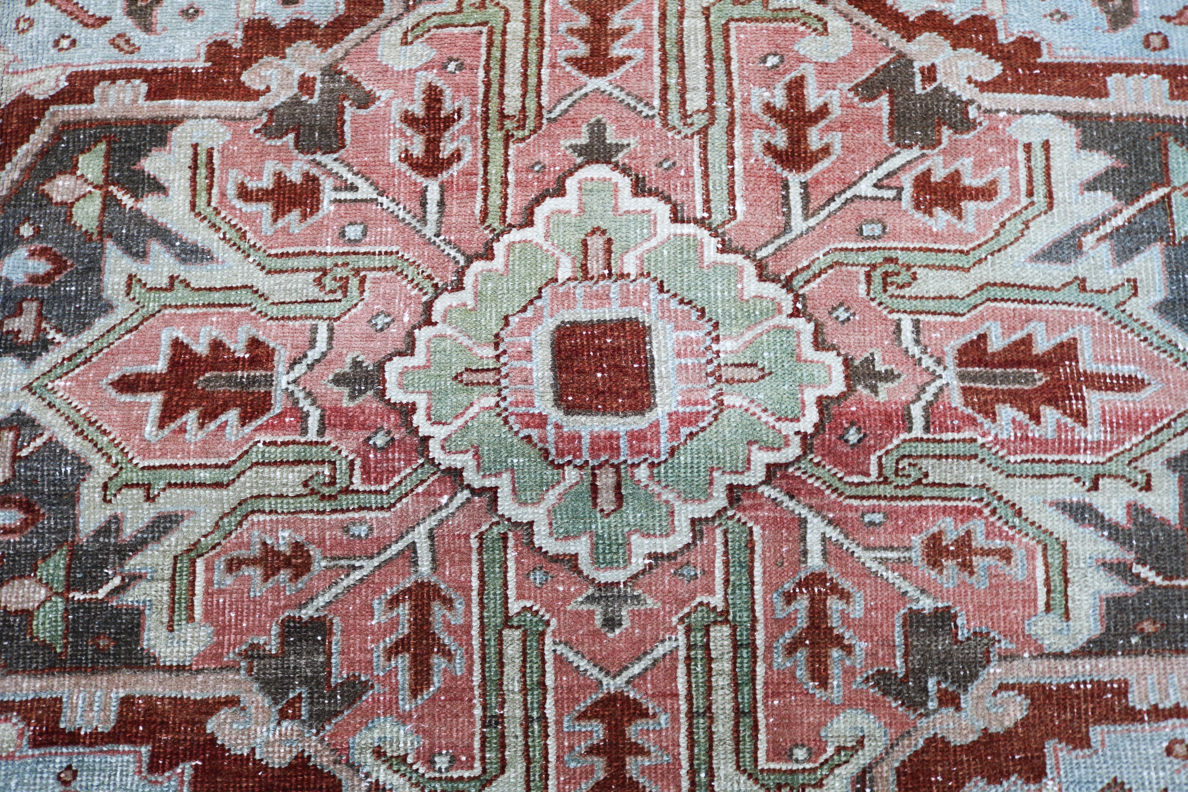 Close-up detail of antique Persian Heriz rug showing handwoven geometric motifs and natural wool colours