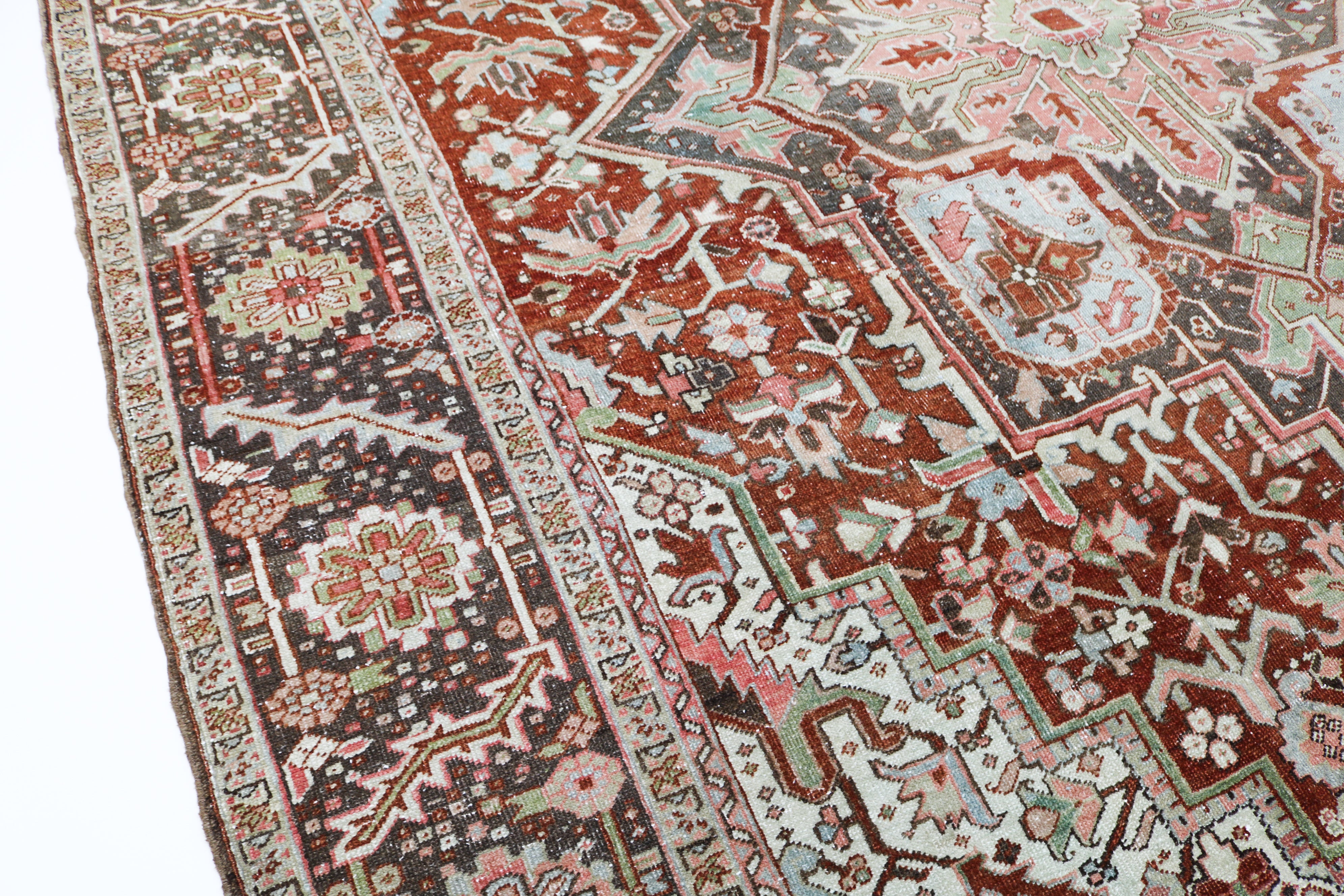 Close-up detail of antique Persian Heriz rug showing handwoven geometric motifs and natural wool colours