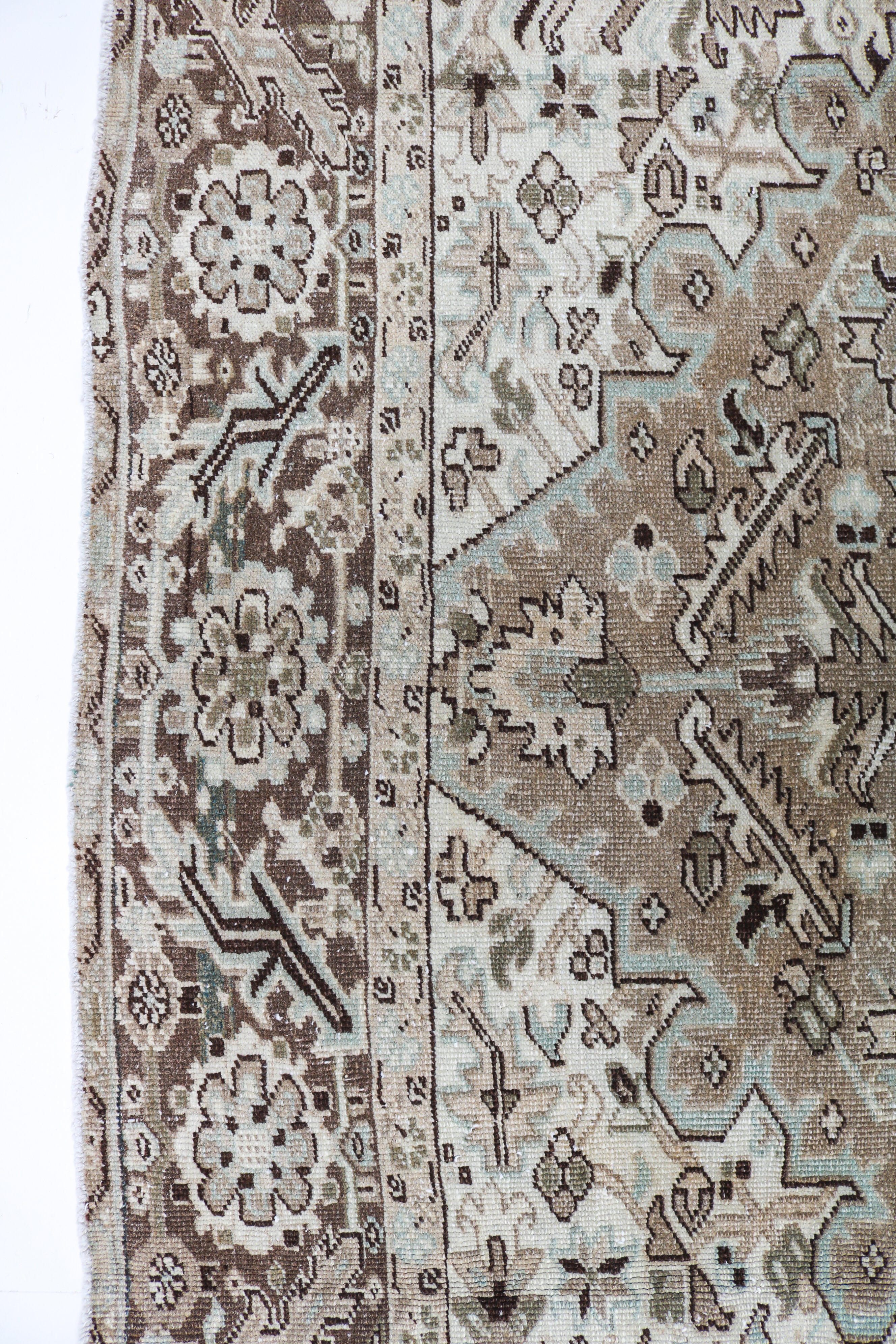 Close-up detail of antique Persian Heriz rug showing handwoven geometric motifs and naturally aged wool colours