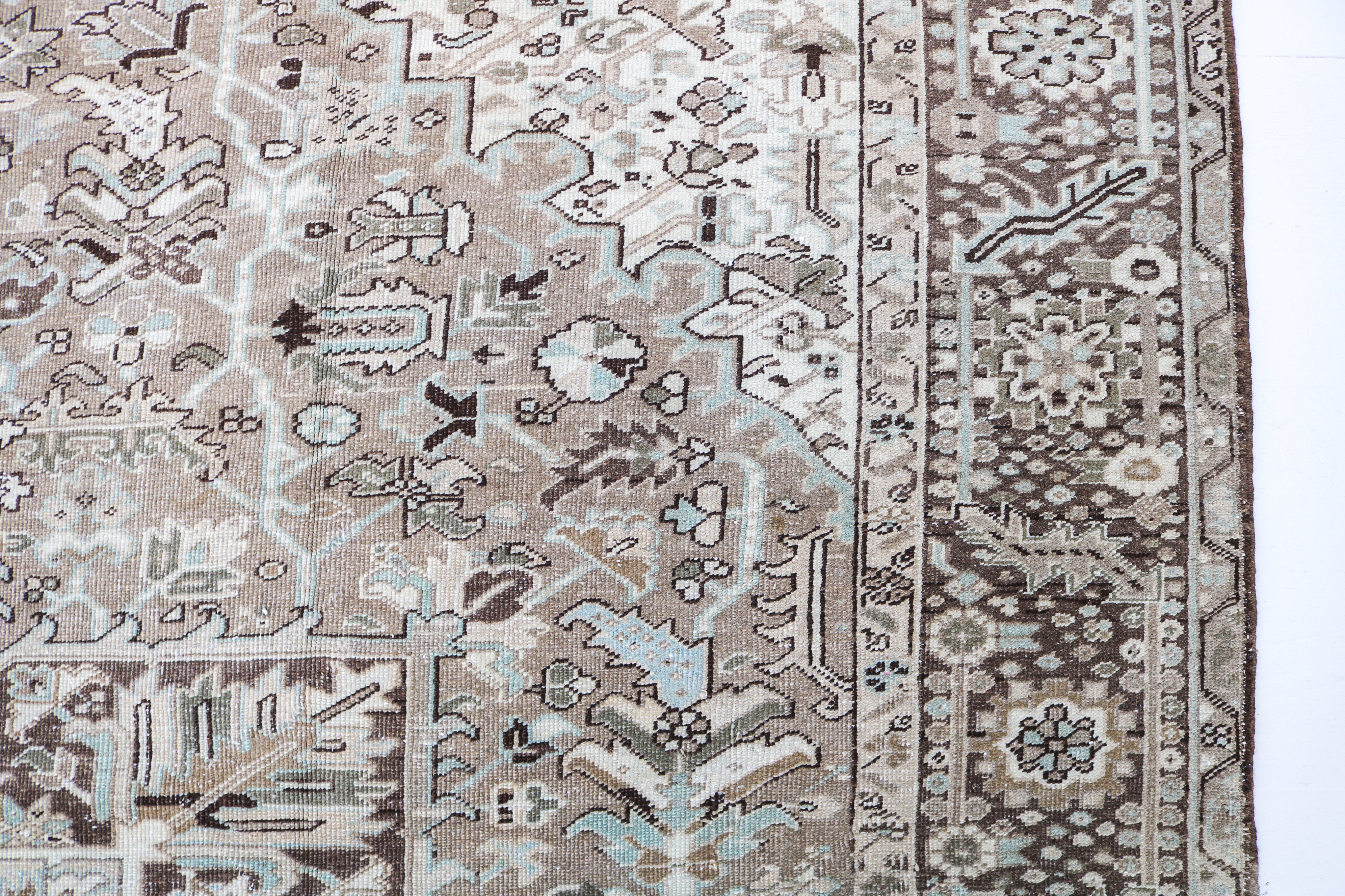 Detail of antique Persian Heriz carpet with geometric tribal motifs and softly faded natural colours