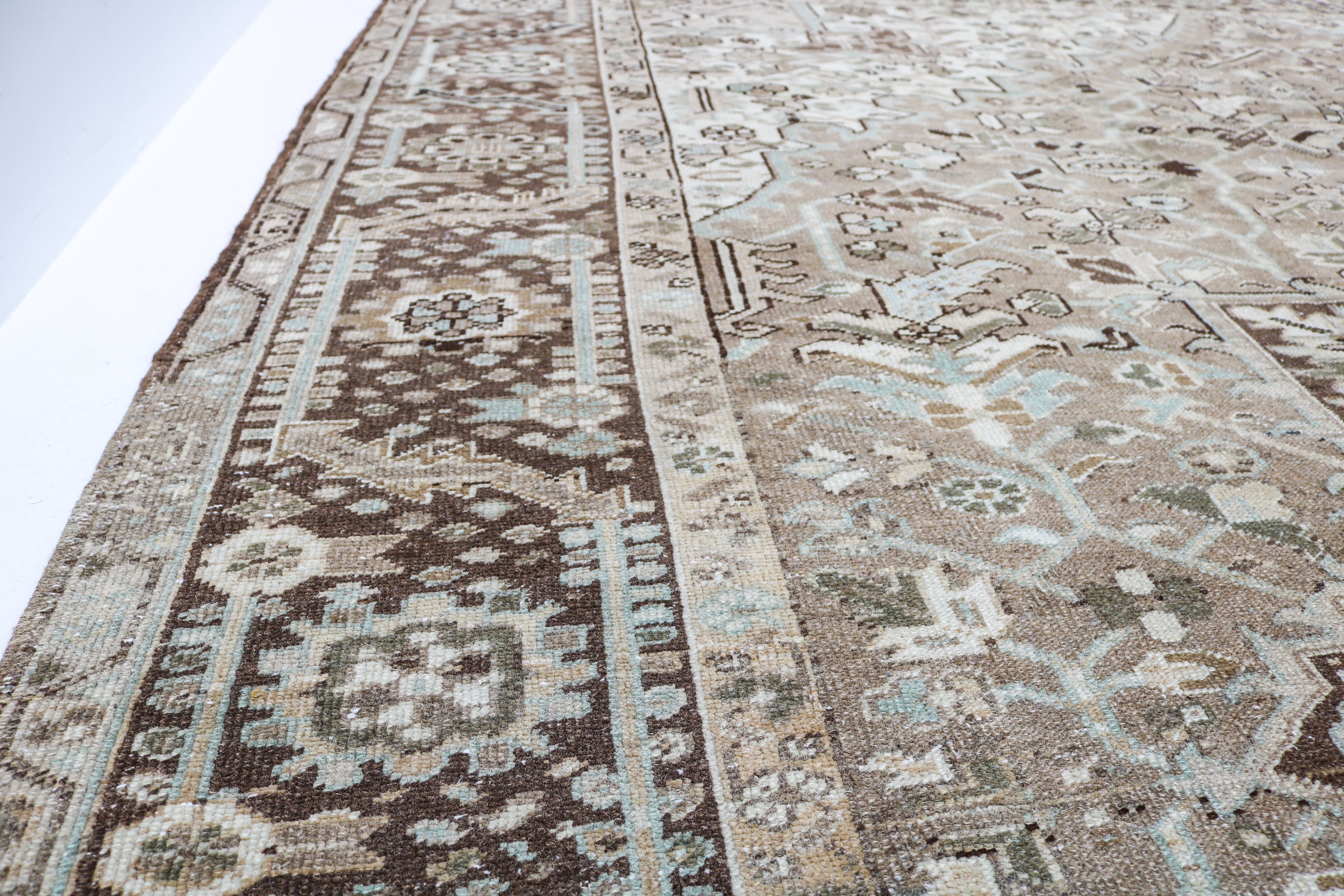Antique Persian carpet close-up showing fine geometric weaving and subtle colour variation