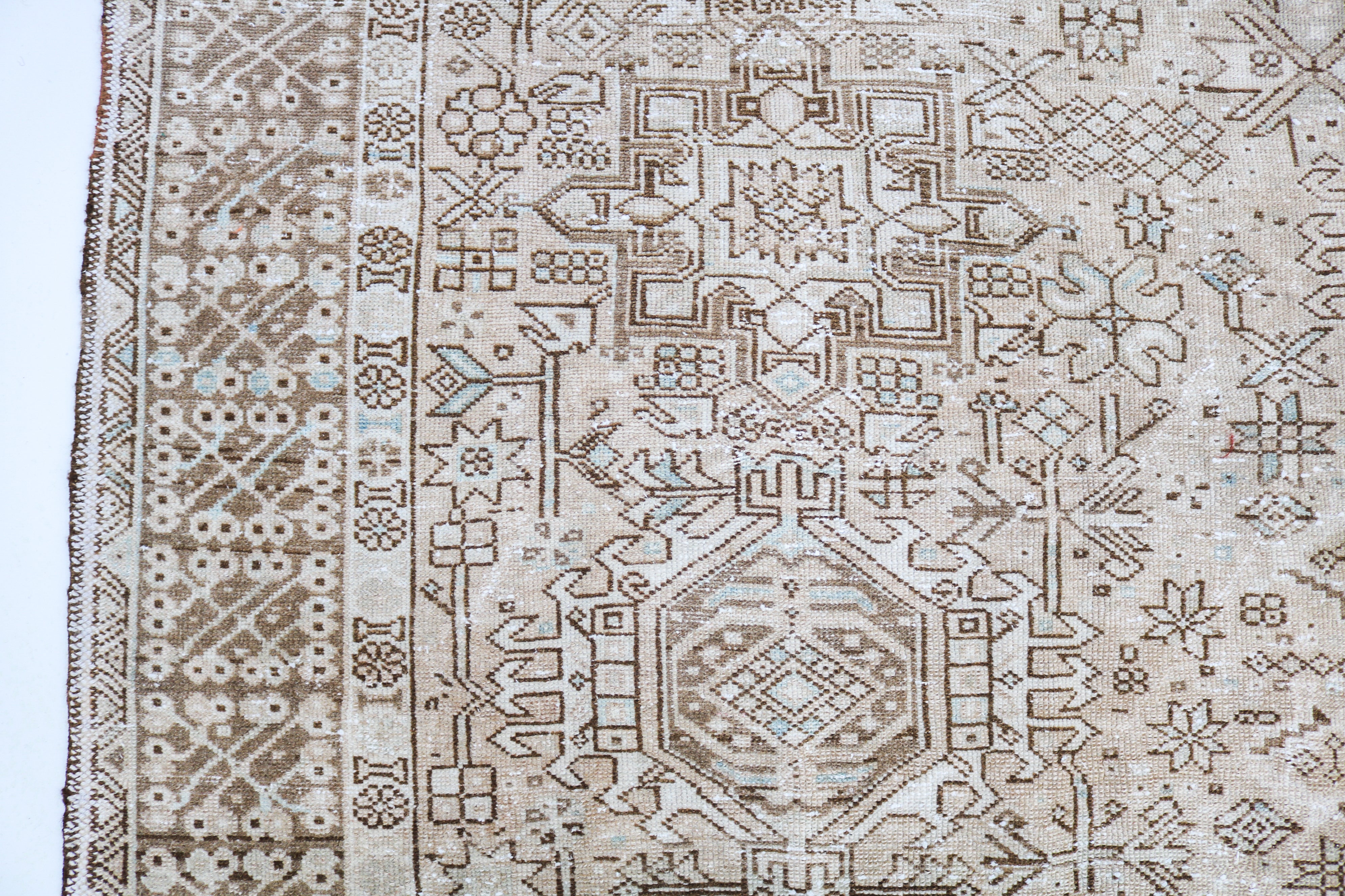 Close-up of hand-knotted Persian Heriz-Karaja rug showing geometric border patterns and aged patina