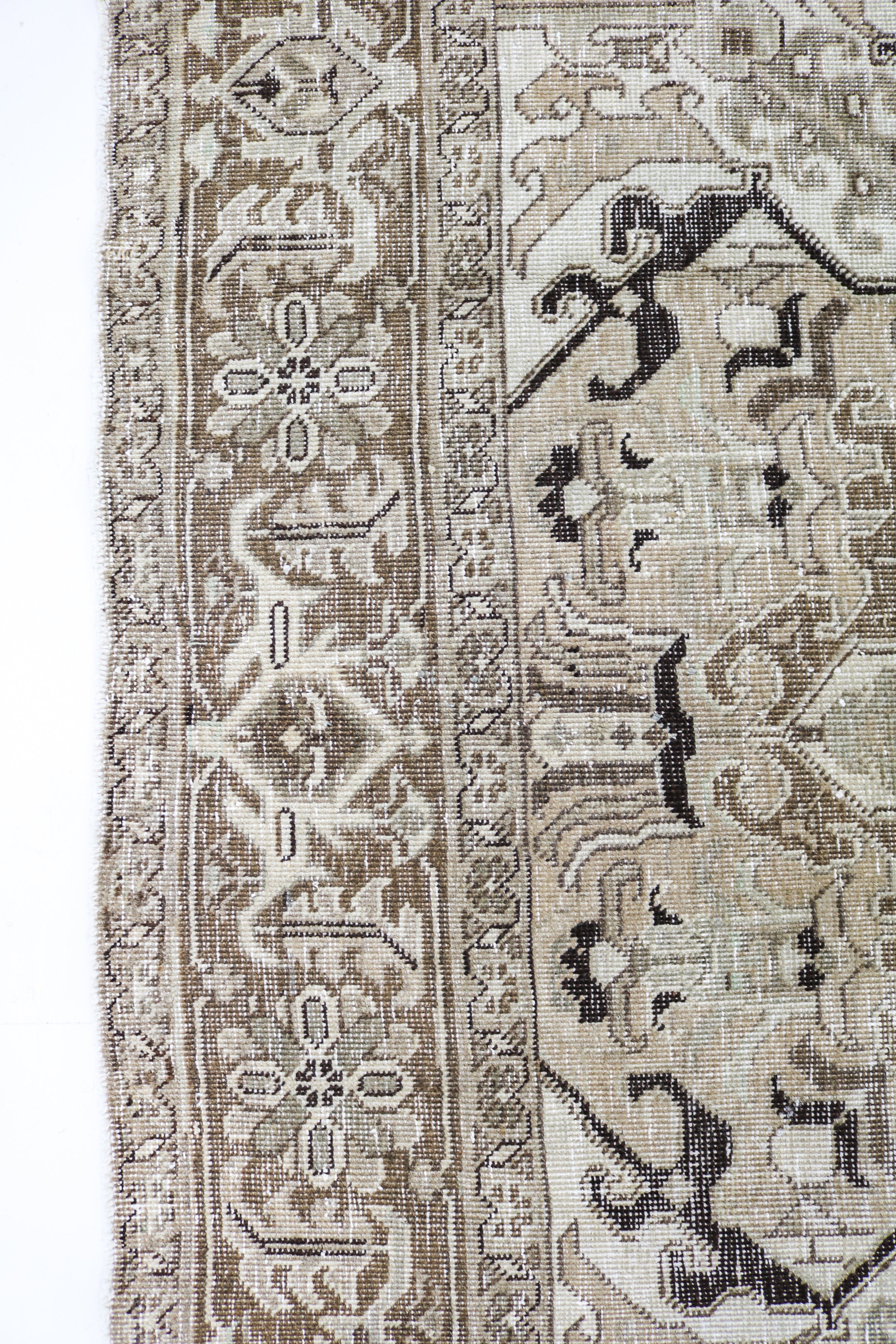 Close-up of hand-knotted Persian rug showing intricate border patterns and aged patina