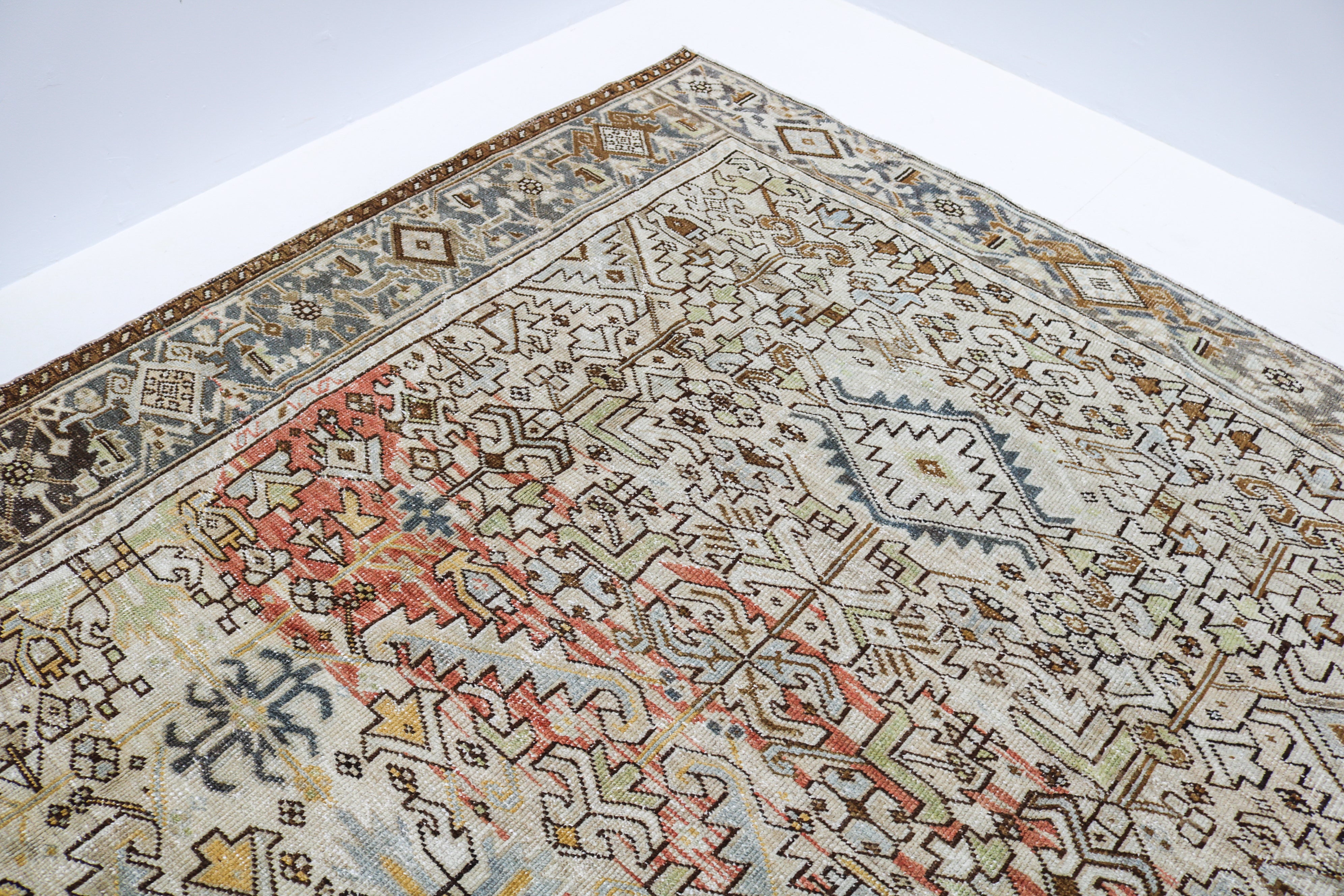 Close-up of hand-knotted Persian Heriz rug showing intricate border patterns and authentic aged patina