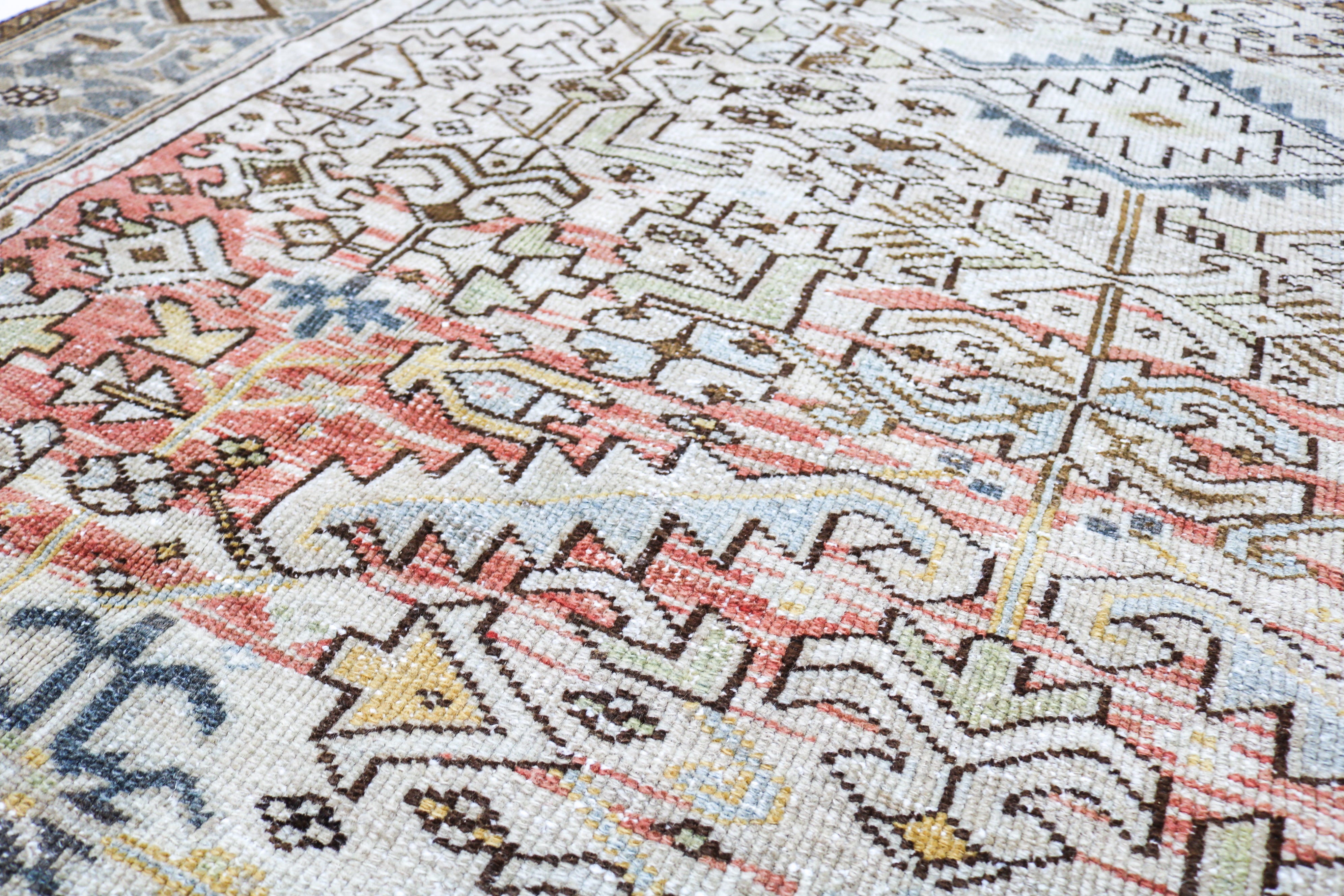 Close-up detail of antique Persian Heriz rug showing handwoven tribal motifs and aged wool colours