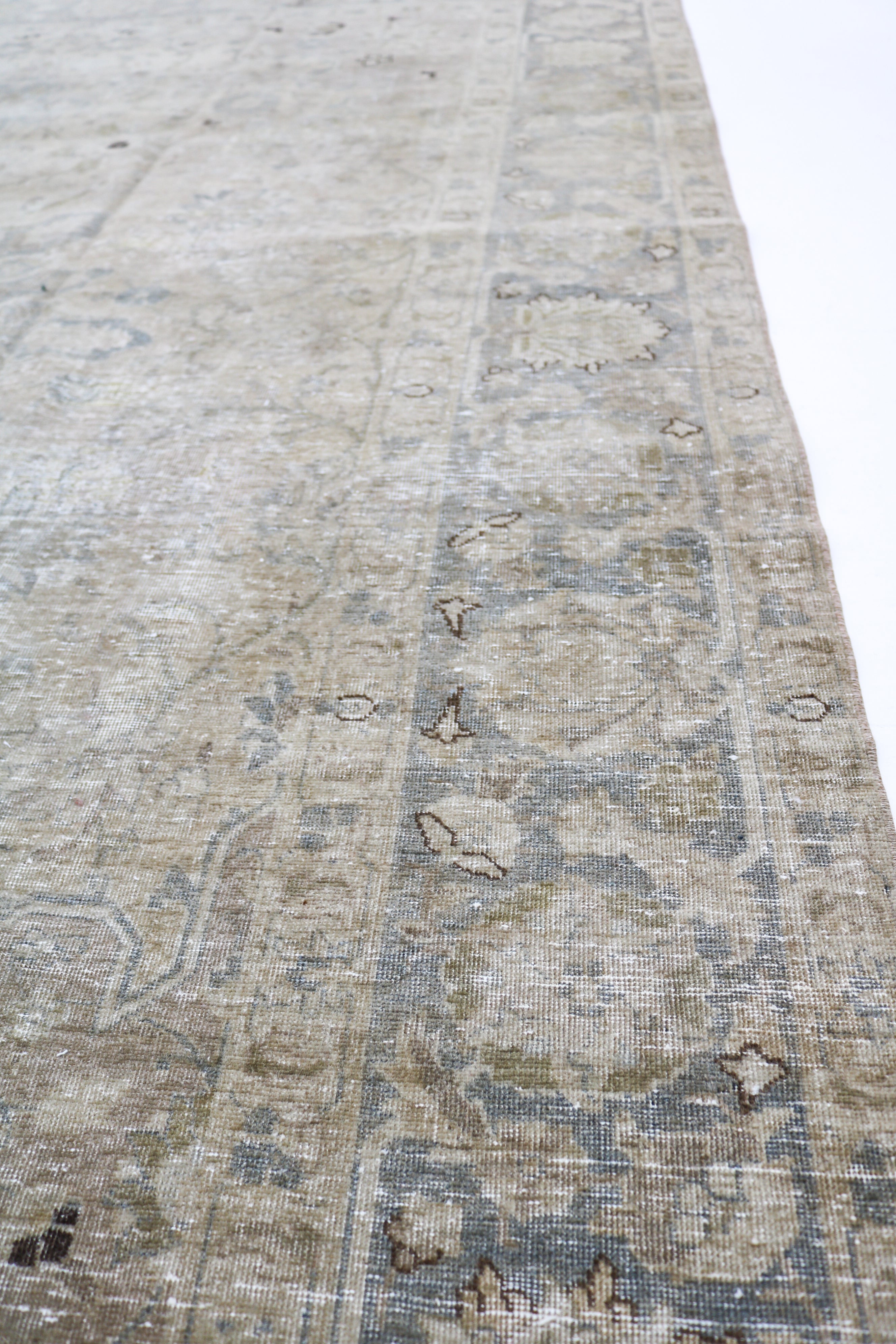 Antique Tabriz carpet detail featuring elegant floral design and subtle ivory accents