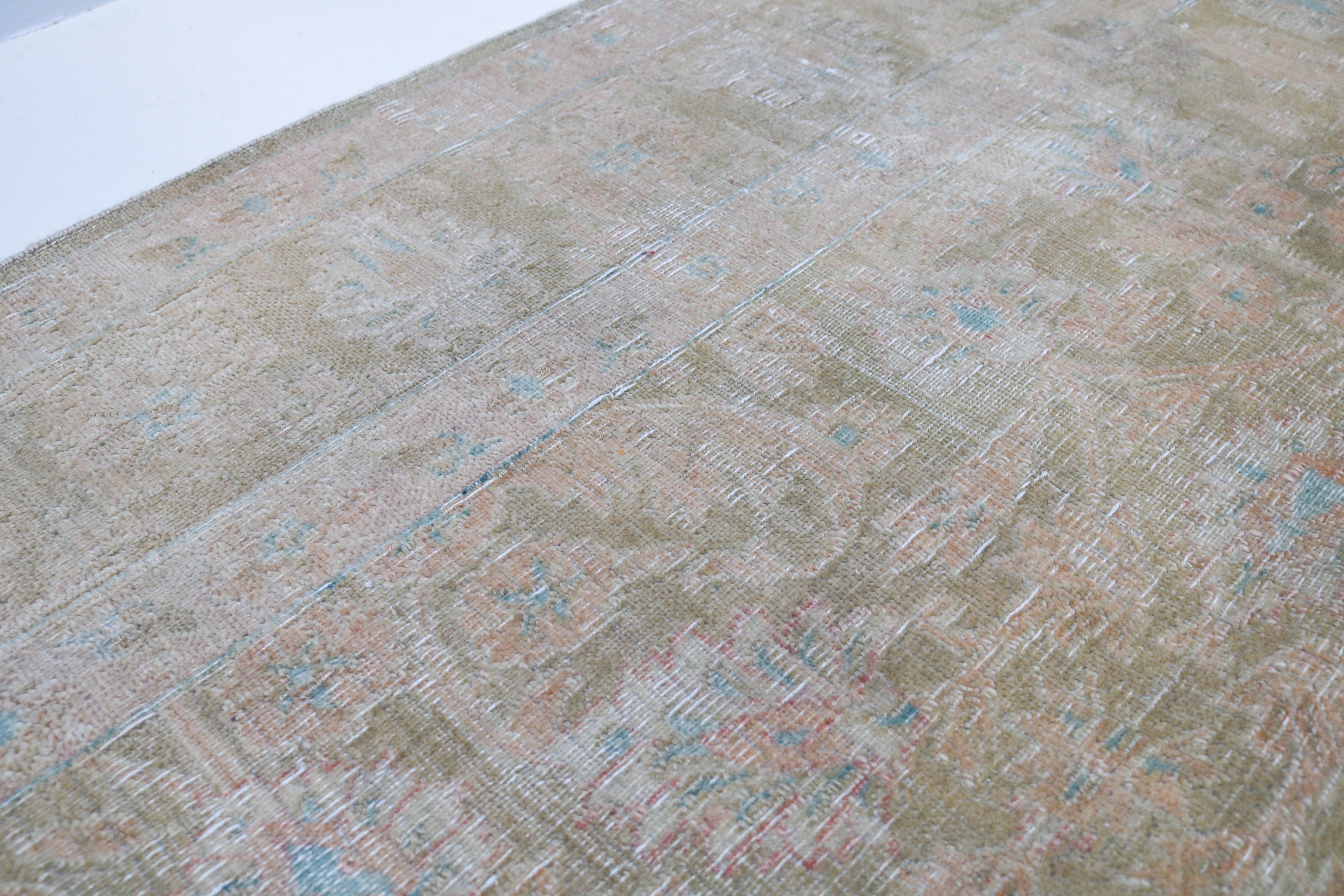 Vintage Sarouk carpet detail featuring refined floral design and subtle blush accents