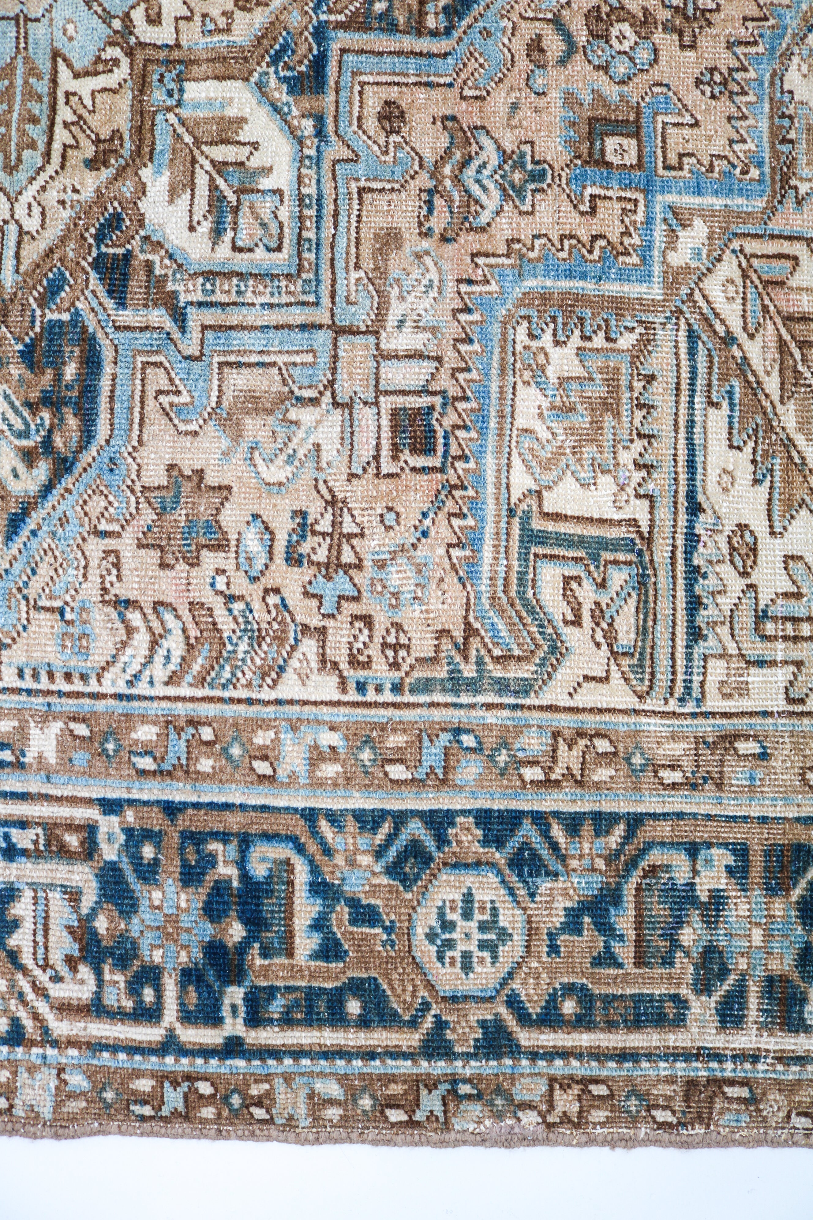Detail of antique Persian Heriz rug with geometric tribal motifs and naturally faded blue tones