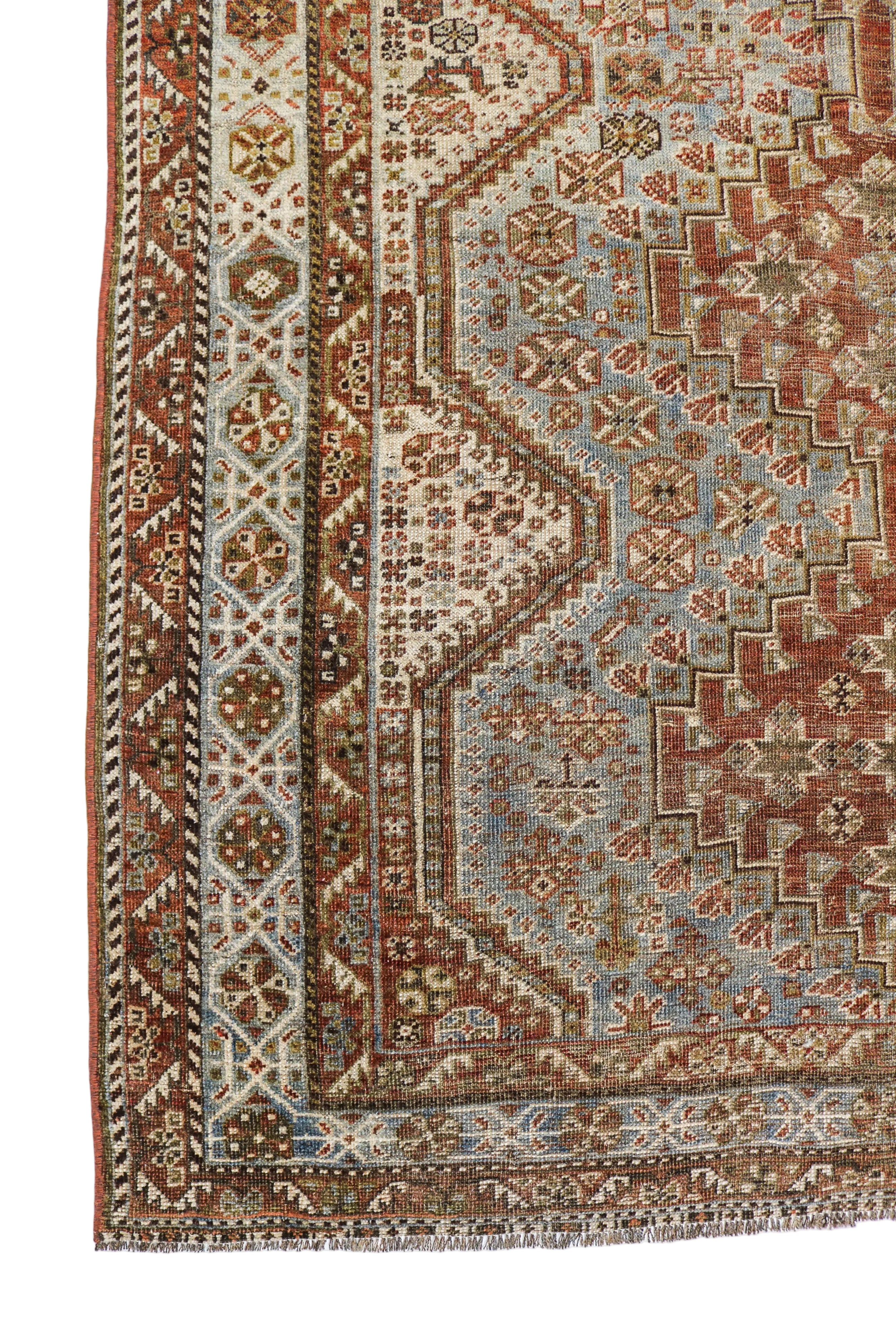 Antique Persian Qashqai rug corner detail with tribal geometric border and terracotta tones circa 1920