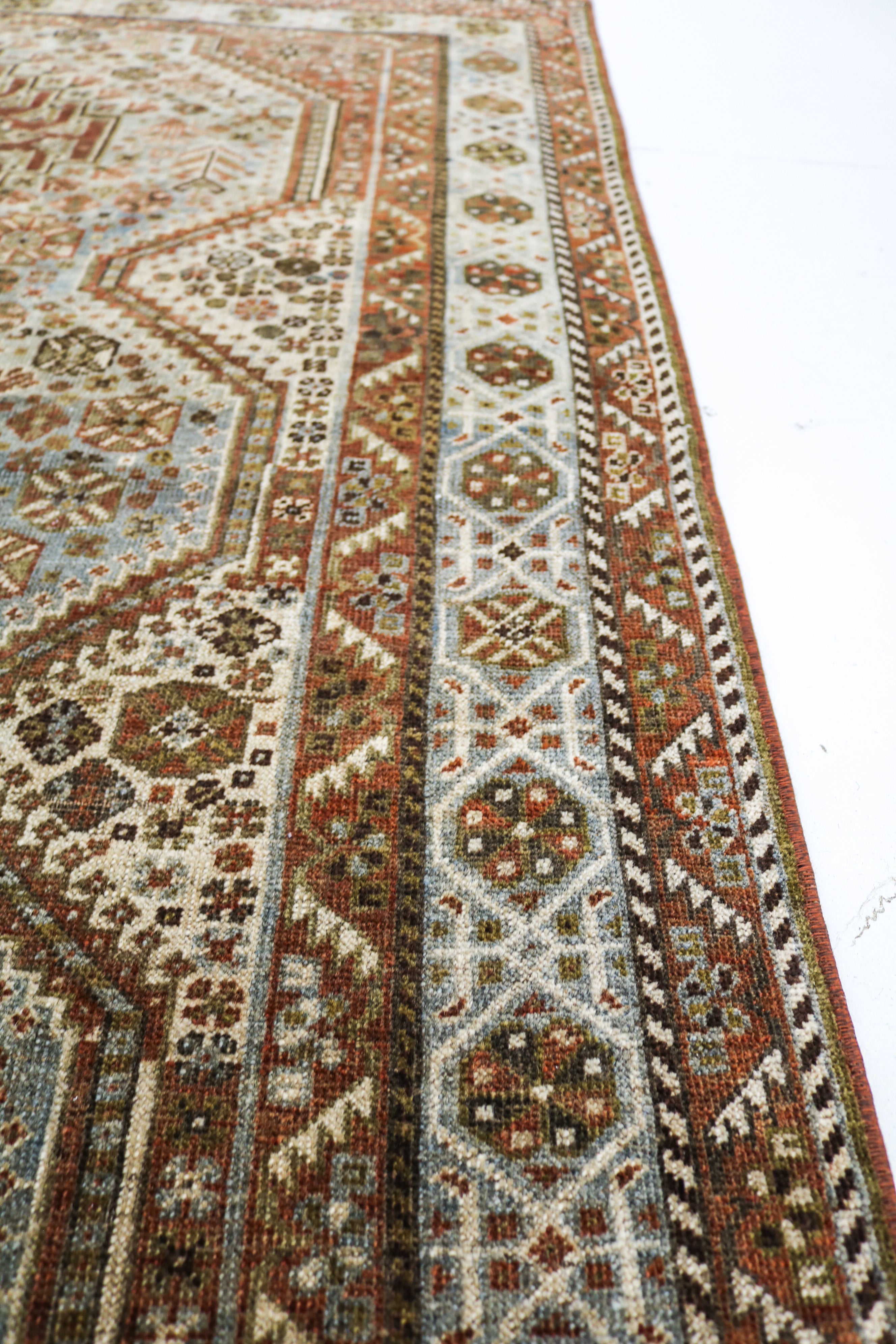 Close-up of hand-knotted Persian Qashqai rug showing intricate border patterns and authentic aged patina